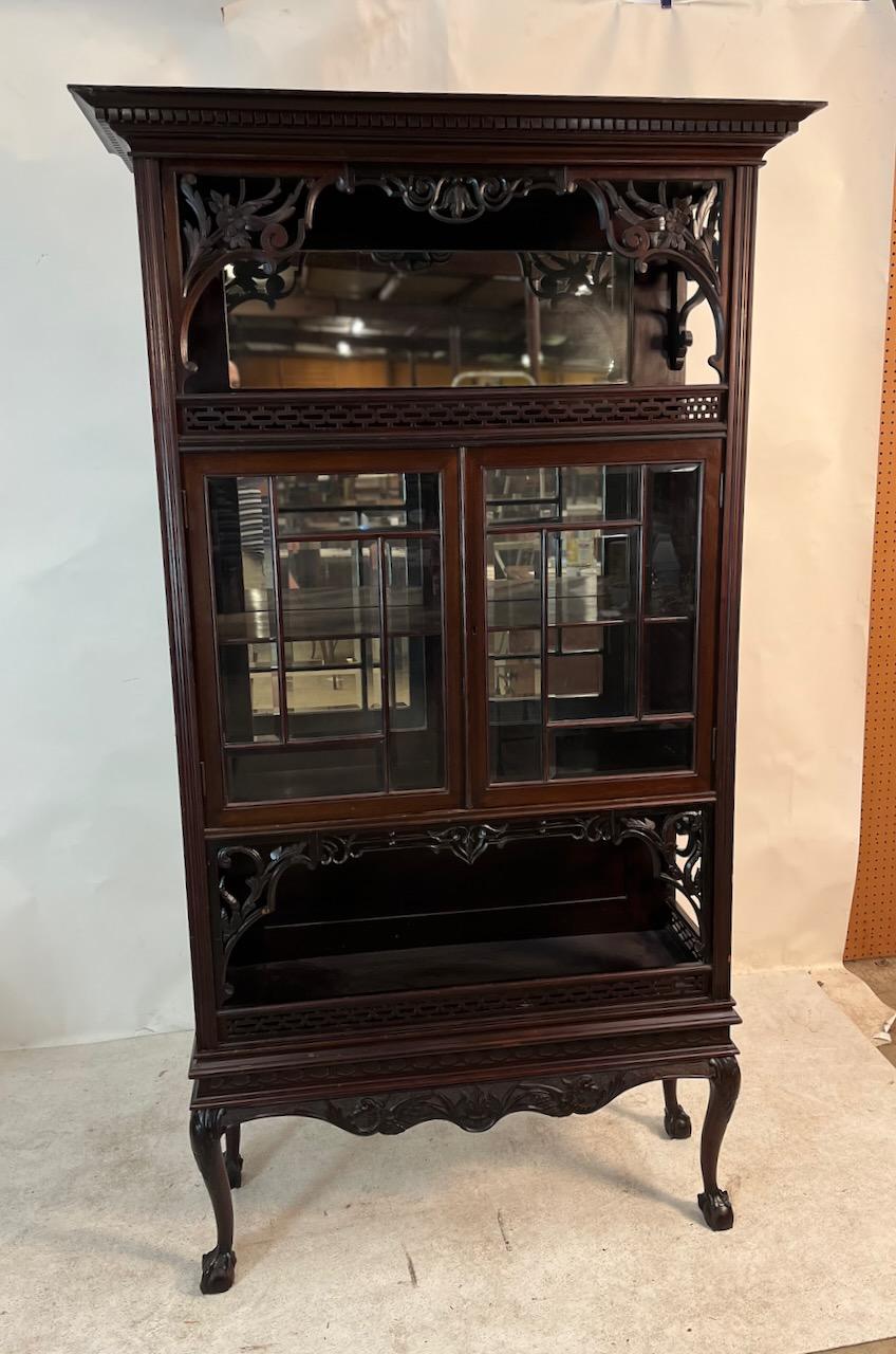 Late Victorian standing vitrine/display cabinet with examples of many different styles:  Chippendale ball and claw legs, open fretwork, deco style floral decoration.  Mirrored display with two doors and open self below.