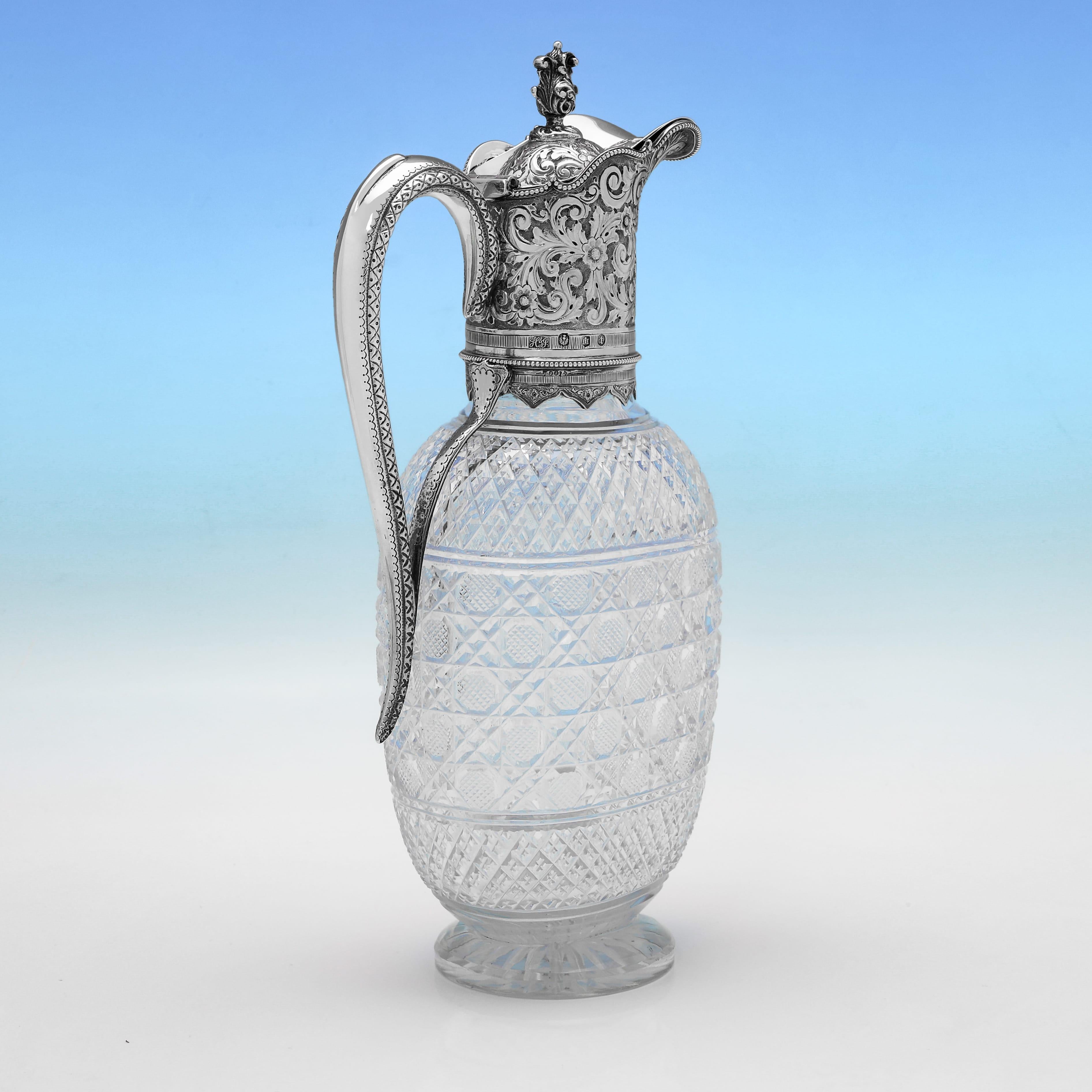 Hallmarked in Edinburgh in 1900 by Hamilton & Inches, this attractive, Victorian, Antique Sterling Silver Claret Jug, is ornate in design, featuring an oval cut glass body, and a decorative silver mount and handle with scroll and acanthus engraving