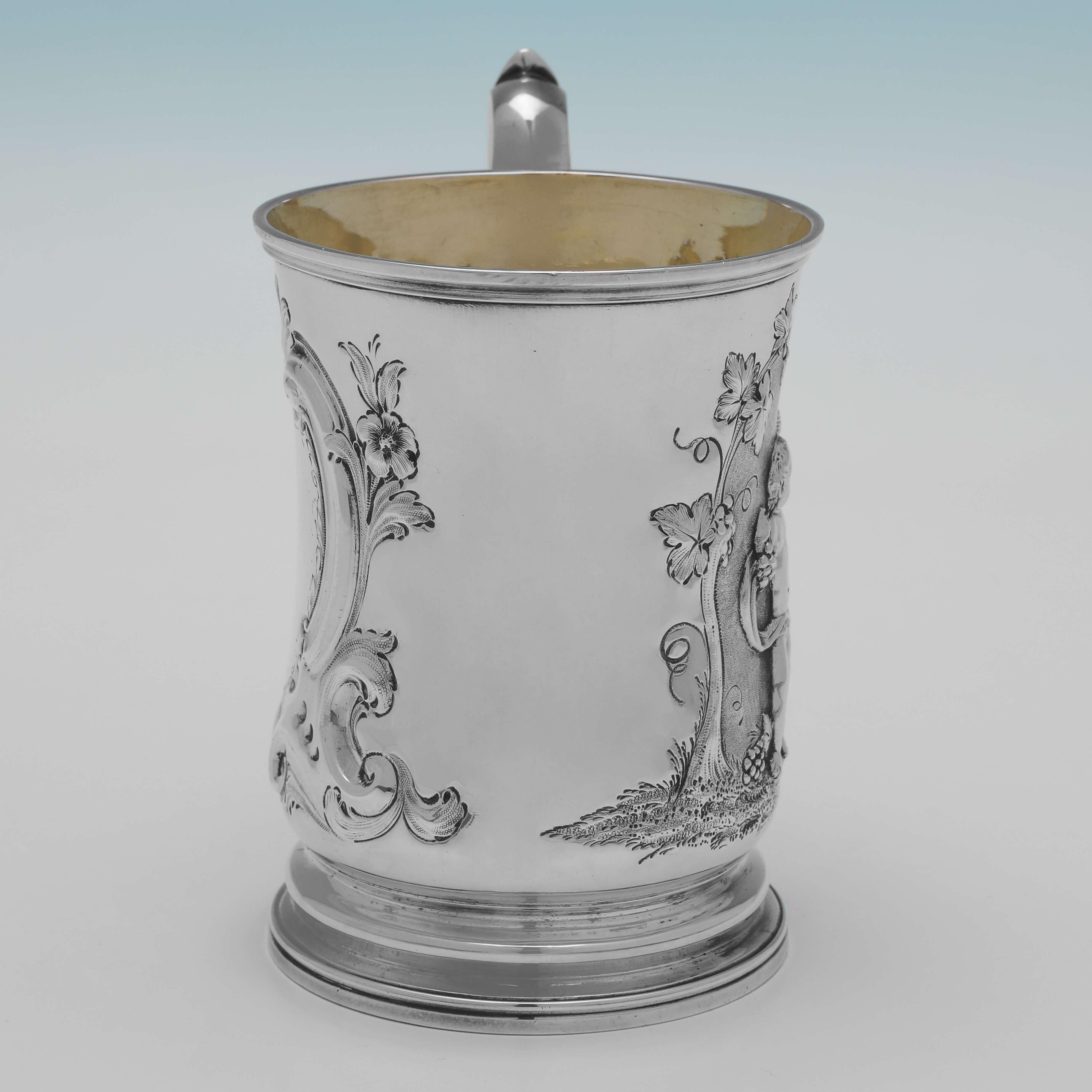 Hallmarked in London in 1856 by Barnards, this charming, Victorian, antique sterling silver christening mug, features a gilt interior and chased decoration to the body, with a scene depicting 2 putti drinking wine. 

The christening mug measures