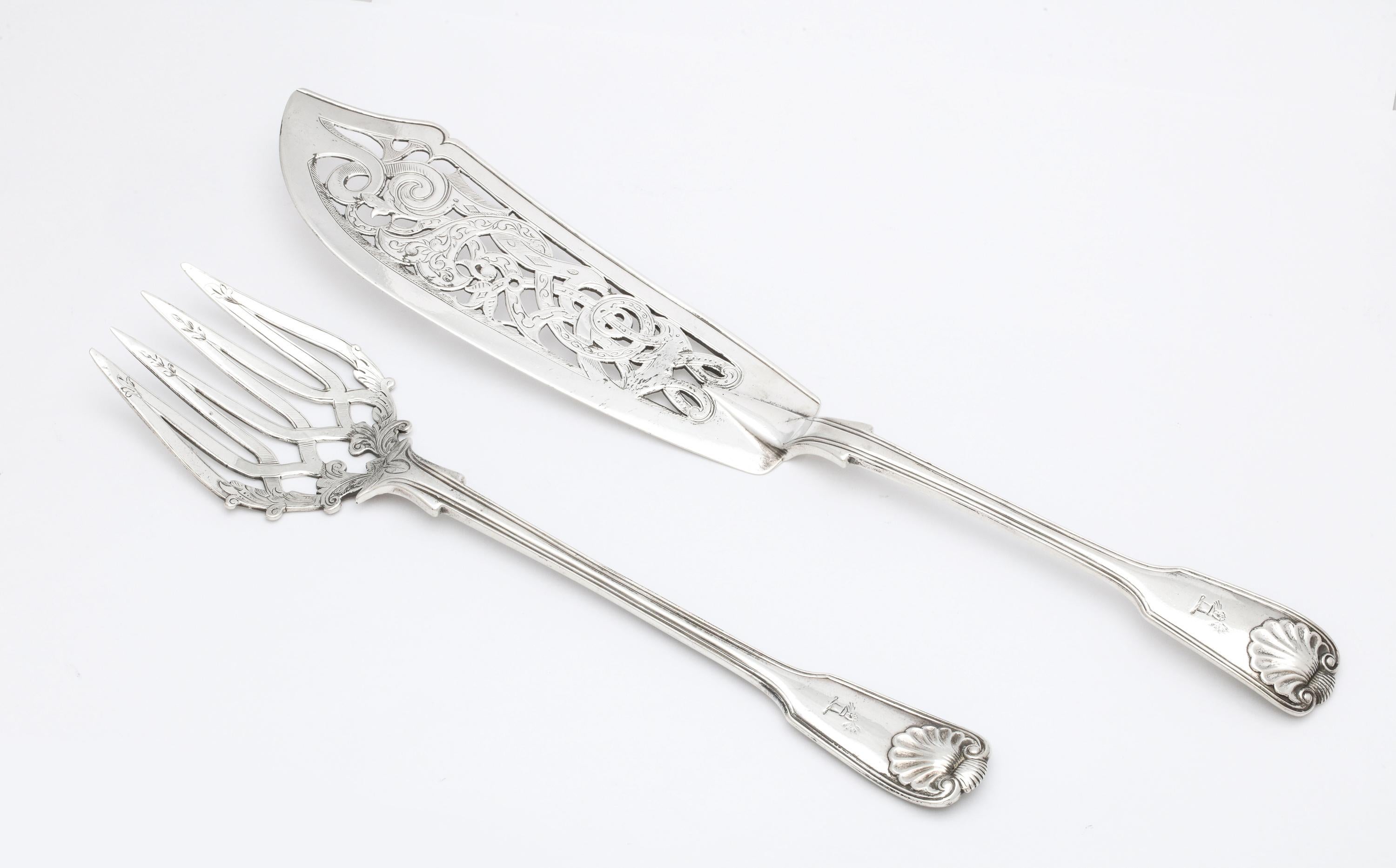 Victorian, sterling silver fish serving set, London, 1855, George Adams - maker. Handles each have an armorial of an extended arm clutching a bunch of arrows. Shell pattern on handles. Knife measures 12 3/4 inches long x 2 inches wide (at widest