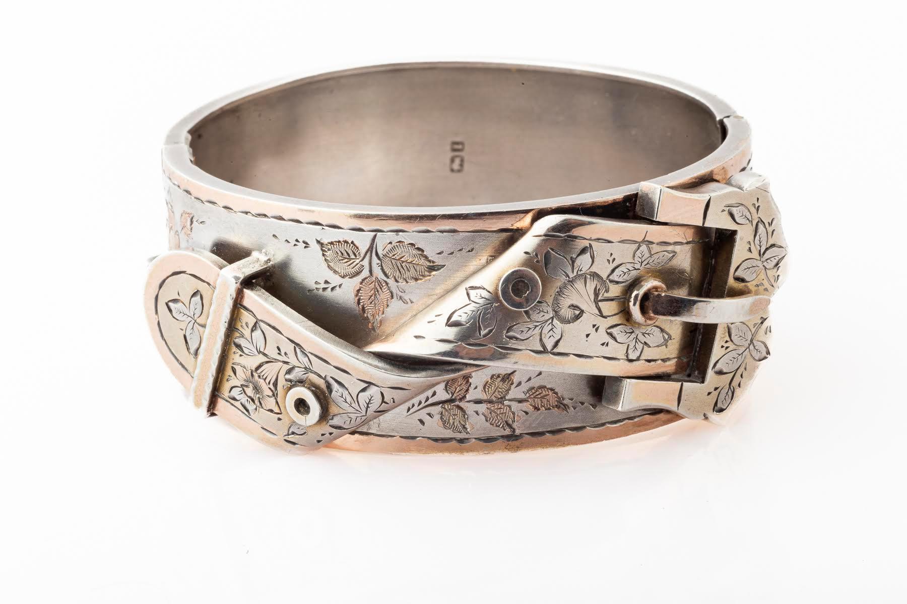 Una fibbia e un cinturino incisi ricoprono l'intera parte anteriore di questo bracciale vittoriano in argento, mentre il retro è semplice e intatto. Ci sono foglie d'oro che evidenziano l'incisione. Come fa un gioielliere a piegare l'argento nel