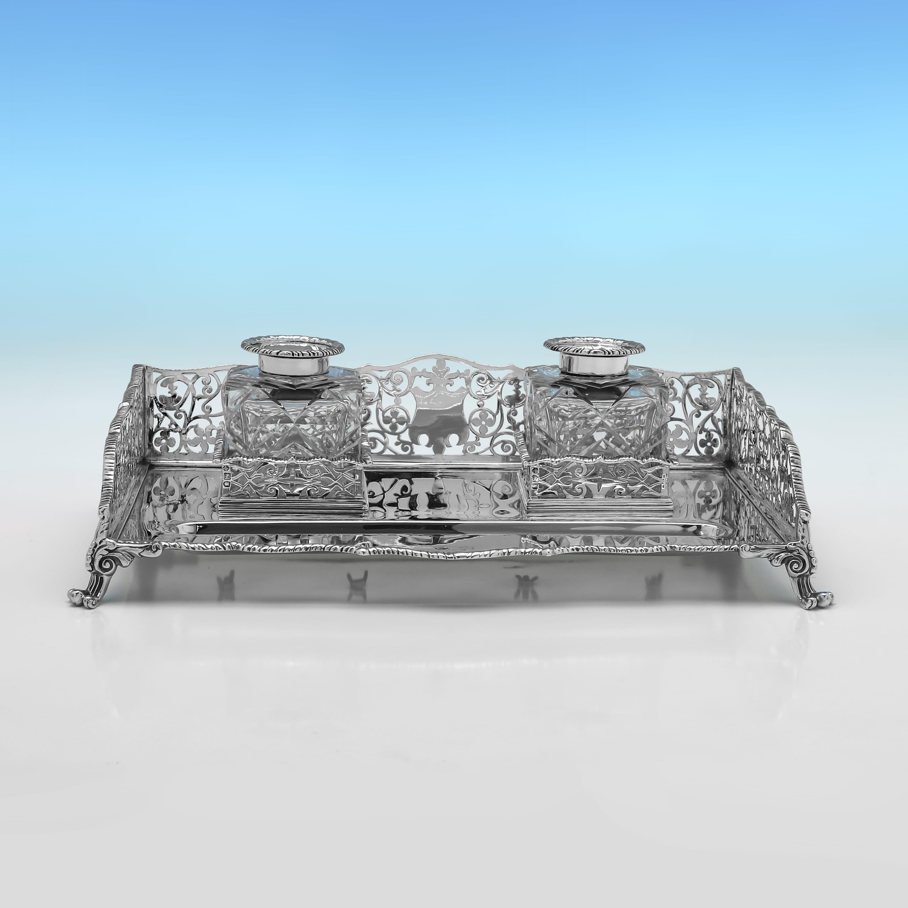 Poinçonné à Londres en 1900 par William Hutton & Sons, cet élégant encrier victorien en argent sterling ancien présente une bordure partagée et percée de style galerie, ainsi que deux encriers en verre taillé avec des montures en argent. Le support