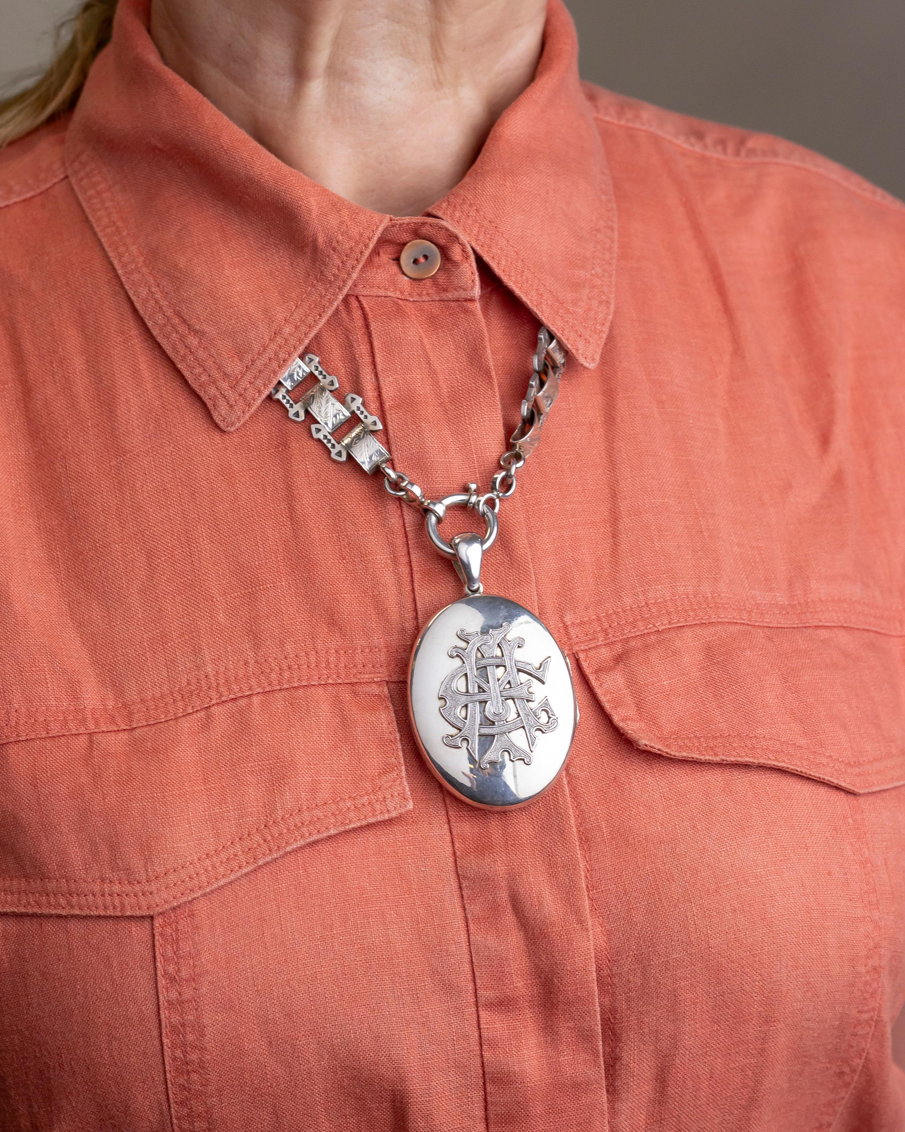 A wonderfully large sterling silver Victorian locket with an elaborate 'Amity, Eternity, Infinity' monogram to the centre front. The oval highly polished locket hangs from a tapering but large bale which allows either a large chain or bolt ring