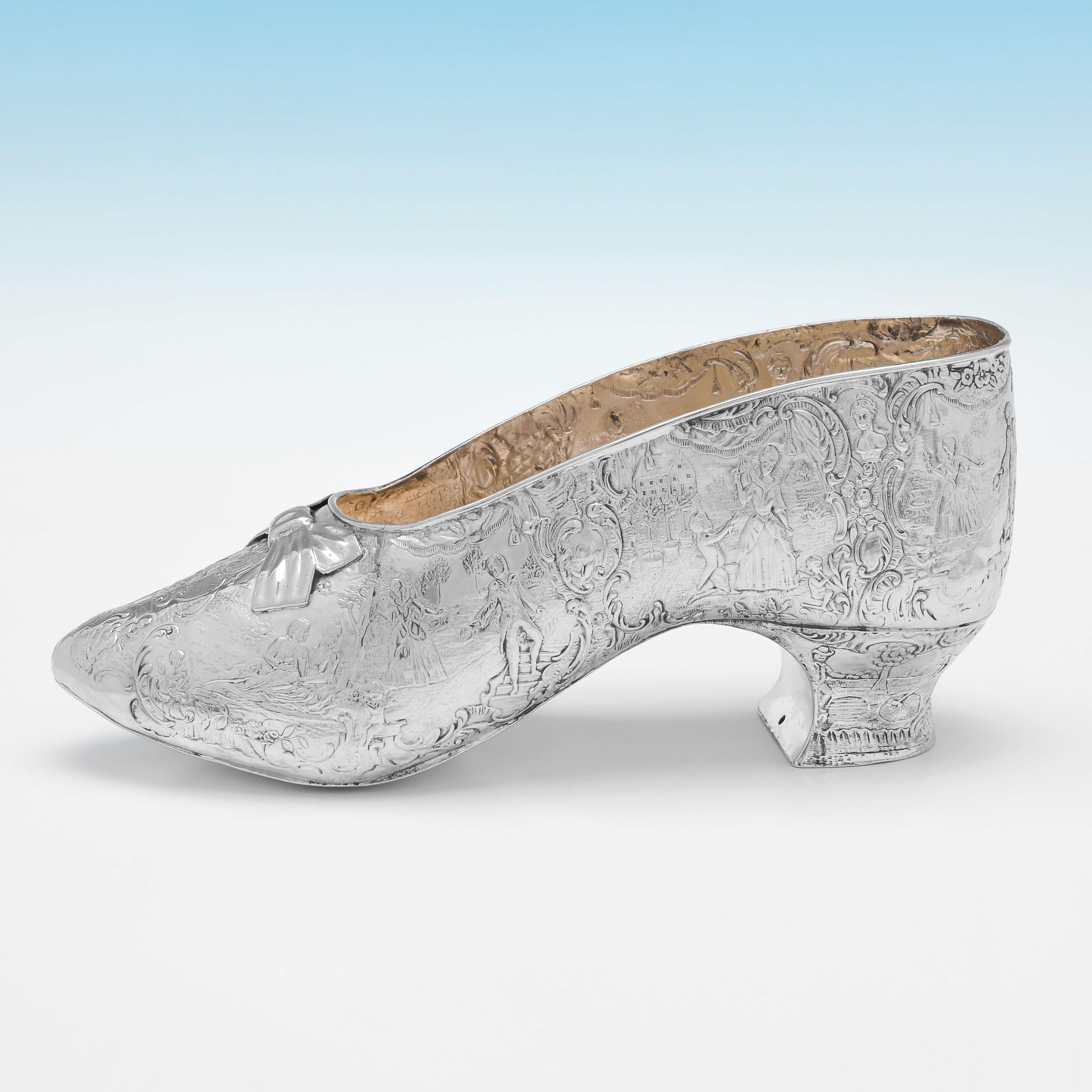 Portant des marques d'importation pour Londres en 1893 par Thomas Goodfellow, ce charmant modèle de chaussure en argent sterling de l'époque victorienne présente un intérieur en verre doré et un magnifique décor ciselé sur toute sa surface. 

Le