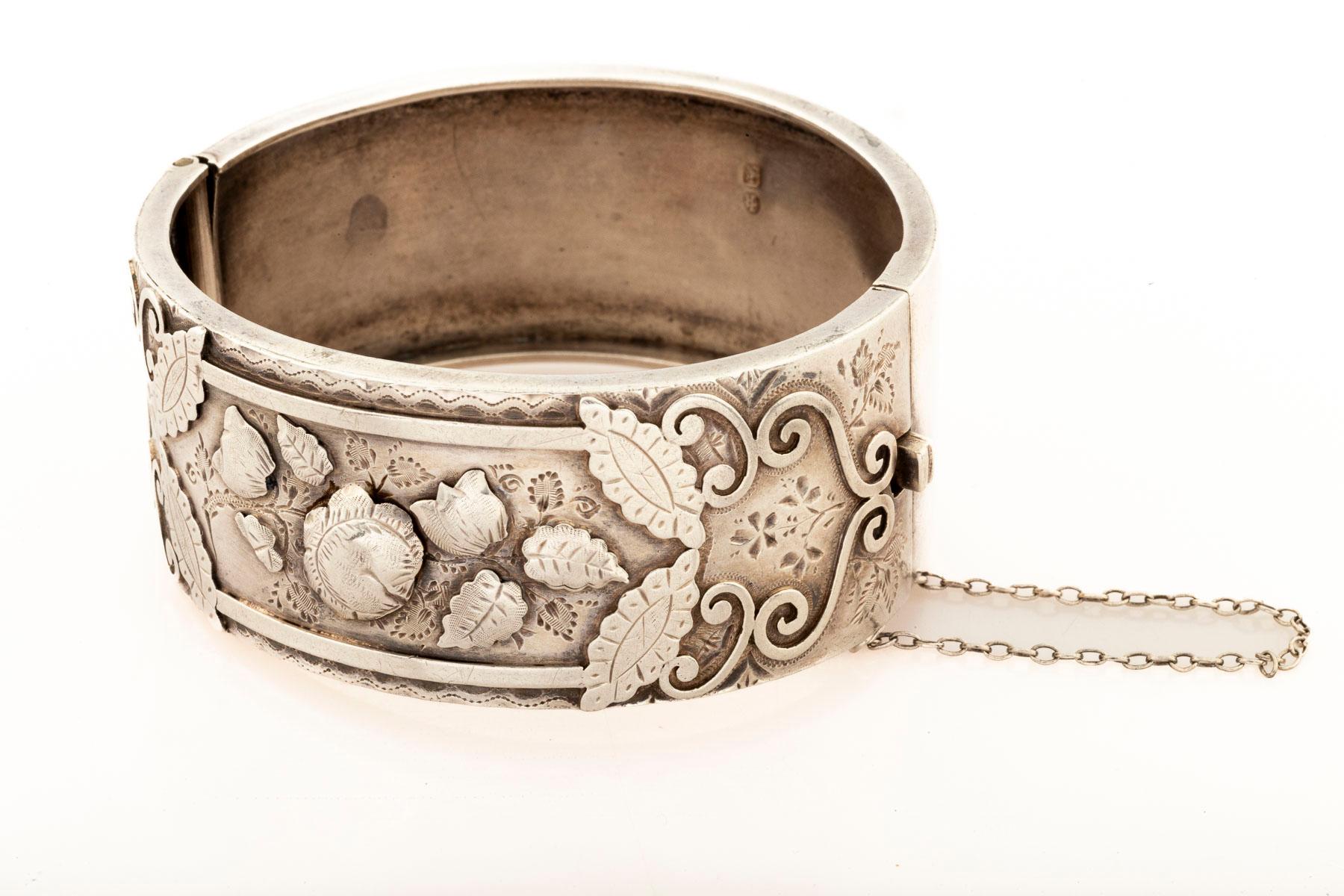 A sterling silver English cuff with repousse blossoms that rise from the silver, The flowers are puffy. Repousse is a technique in which the pattern is punched forward from the back of the jewel. The tulips, roses and leaves seem to dance on the