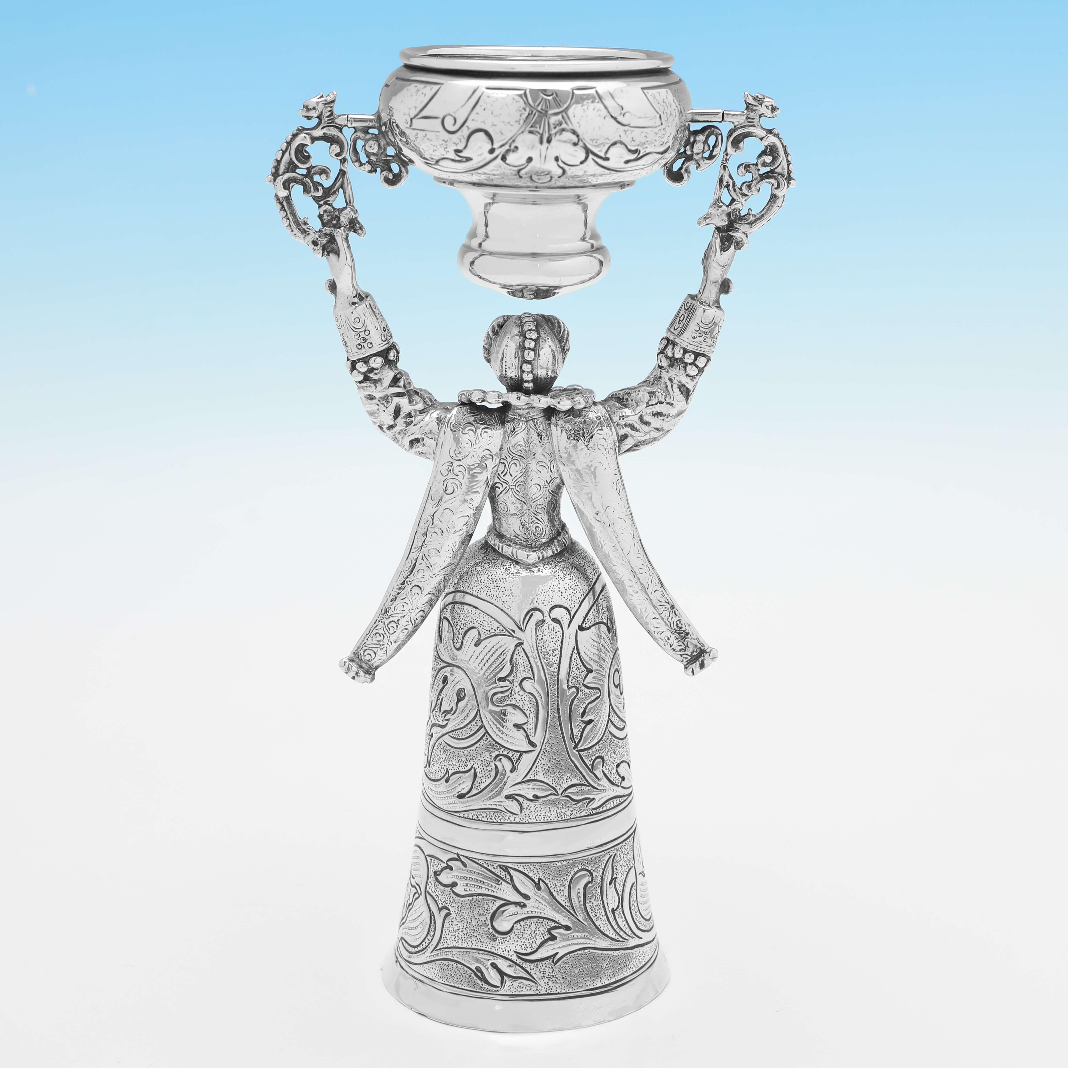 Carrying import marks for Chester in 1900 by Berthold Muller, this charming, Victorian,antique sterling silver wager cup, is modelled as a lady in costume, and features chased decoration throughout. 

The wager cup measures 8.25