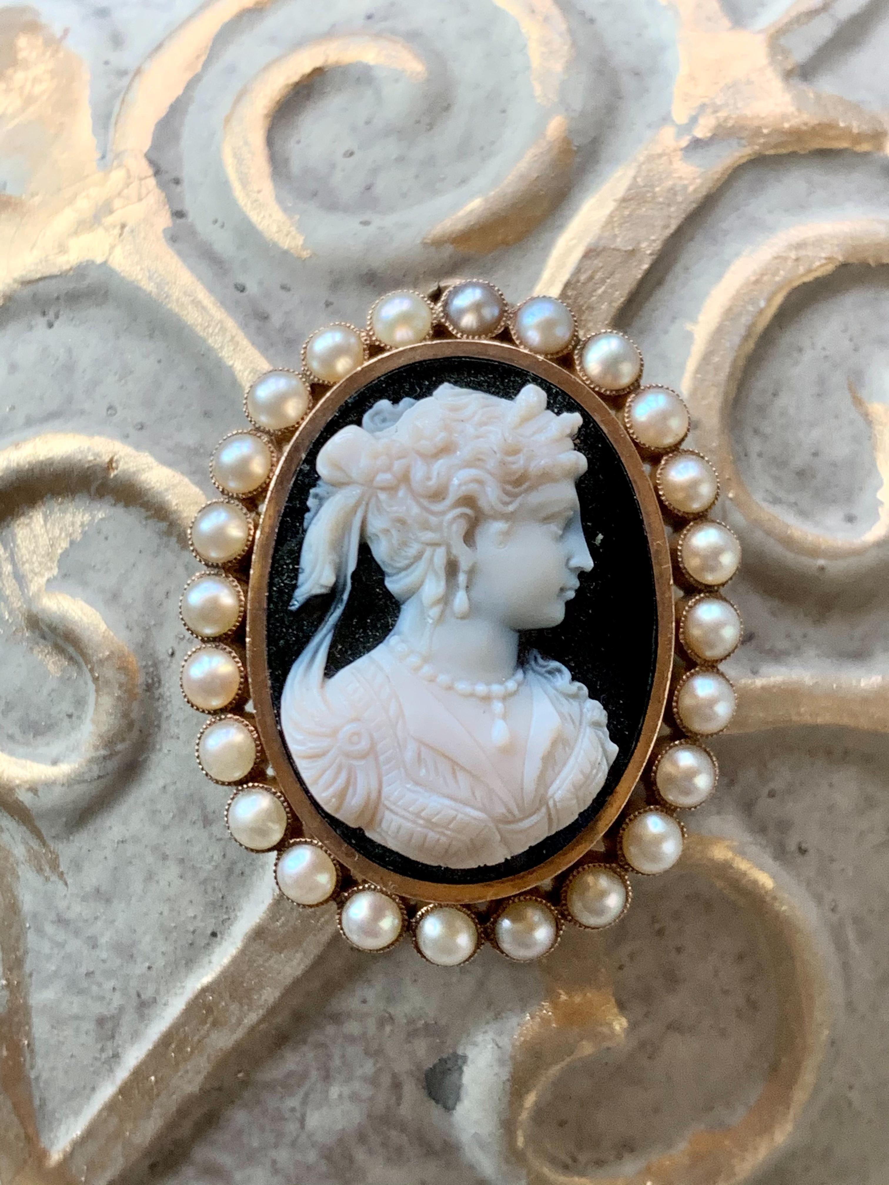 This absolutely fabulous Cameo is carved in black and white stone and features a halo of 24-4mm Pearls. 

The Cameo can be worn as a brooch or a pendant.  Closure is in good working order.

There is no stamp.

Size:  approximately 1 1/2