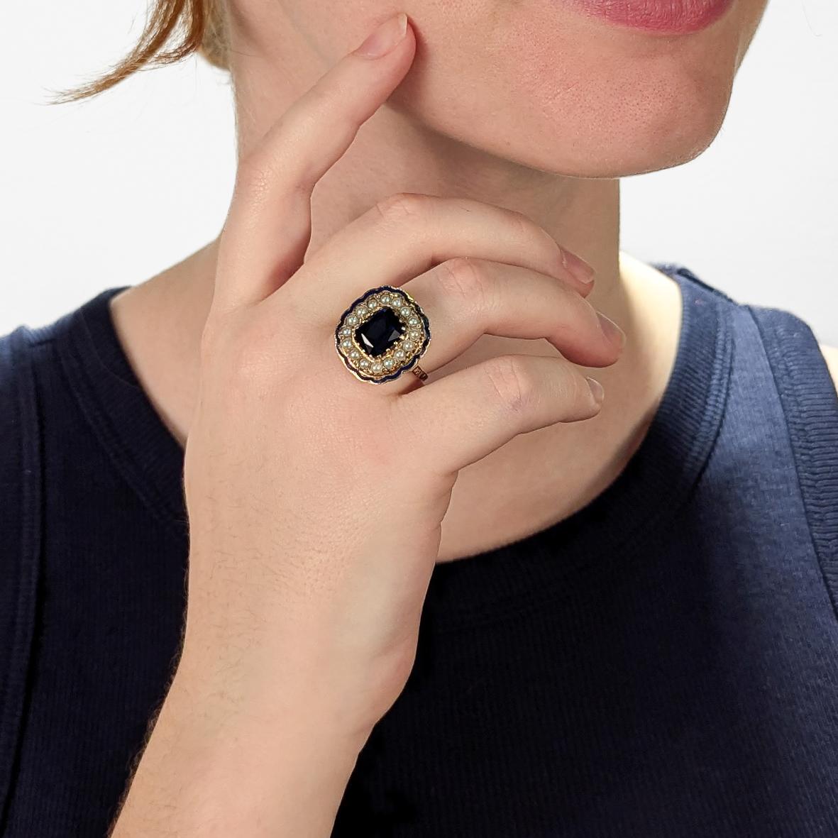 A fine vintage gold, enamel, sapphire, and diamond cocktail ring.

In 14 karat yellow gold.

With a central prong-set 3.68± Ct mixed cushion-cut lab created sapphire surrounded by a halo of 16 round cultured pearls and with cobalt blue enamel trim