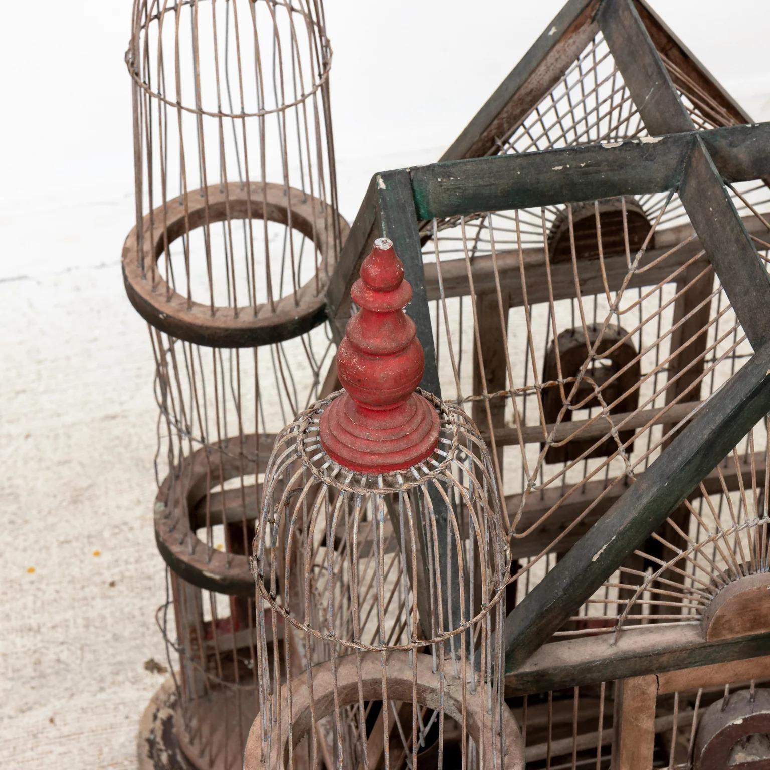 Large Victorian style birdcage featuring a gable roof and four turrets. Distressed painted finish. Please note of wear consistent with age.