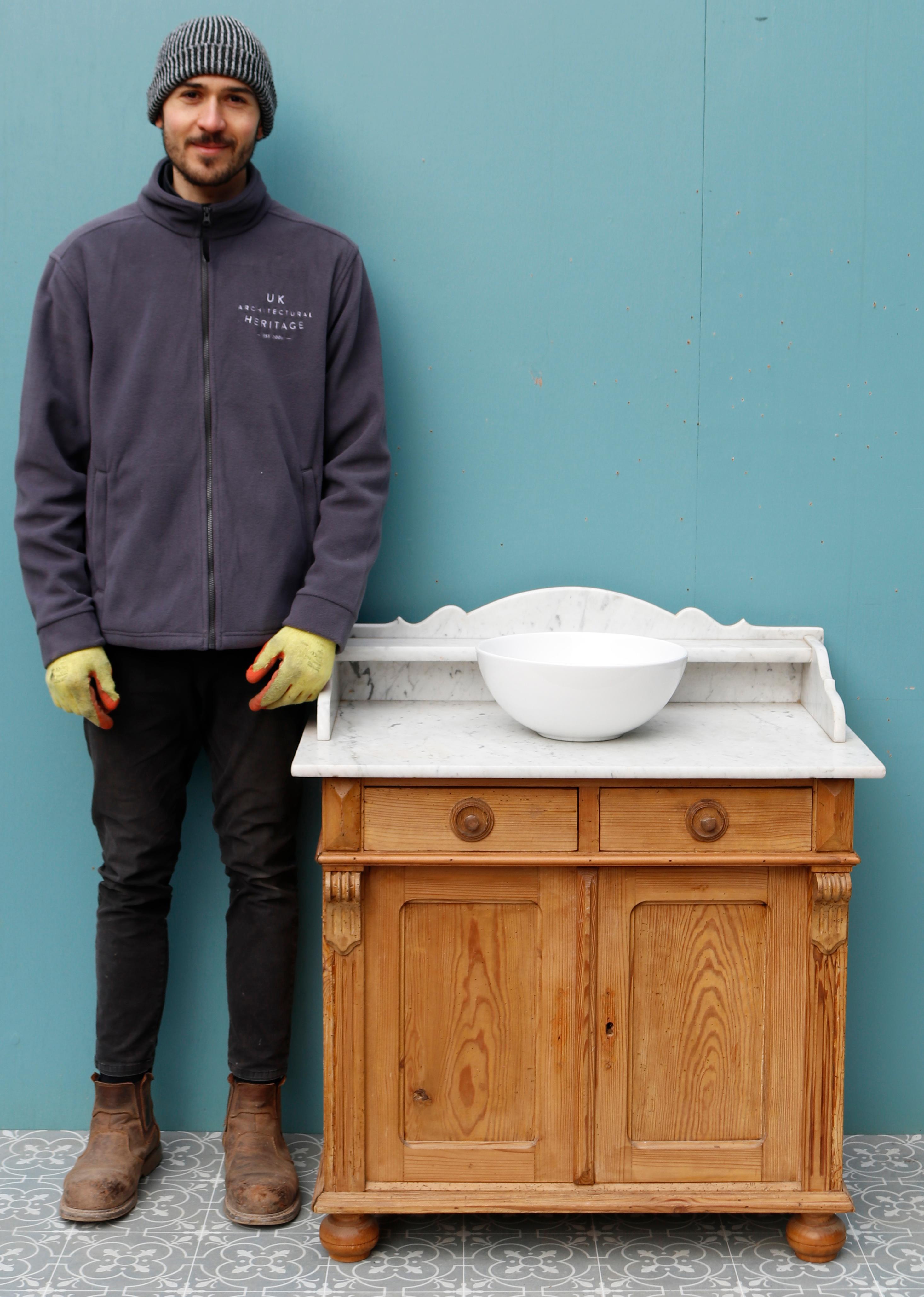 A Victorian style washstand constructed from pine with a Carrara marble top and splash back, supplied with a modern white ceramic bowl. The pine washstand has a wax finish. Previously there has been a small amount of woodworm, but this is not