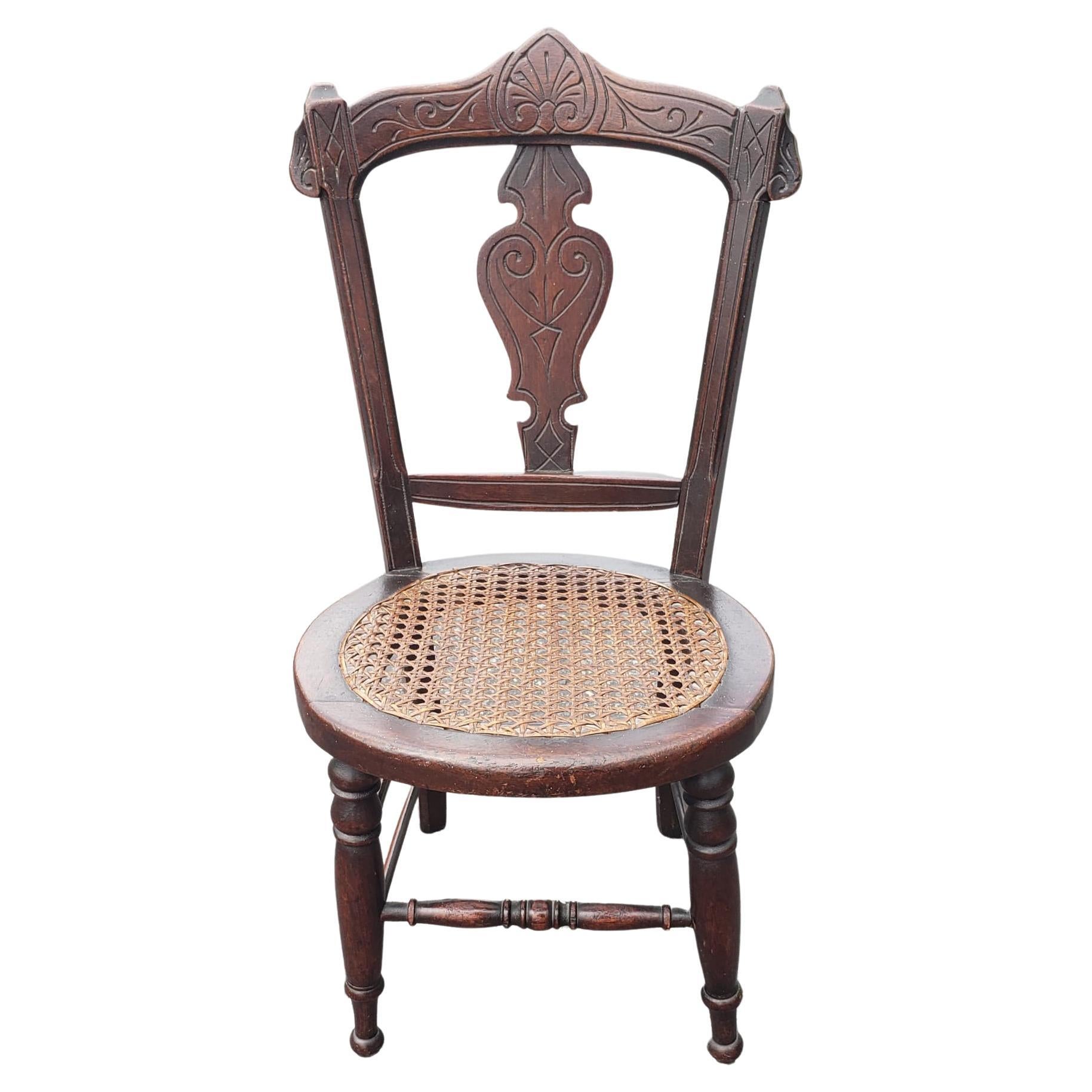 An early 20th century Victorian Style Carved Walnut and Cane Seat Youth Chair in good vintage condition.