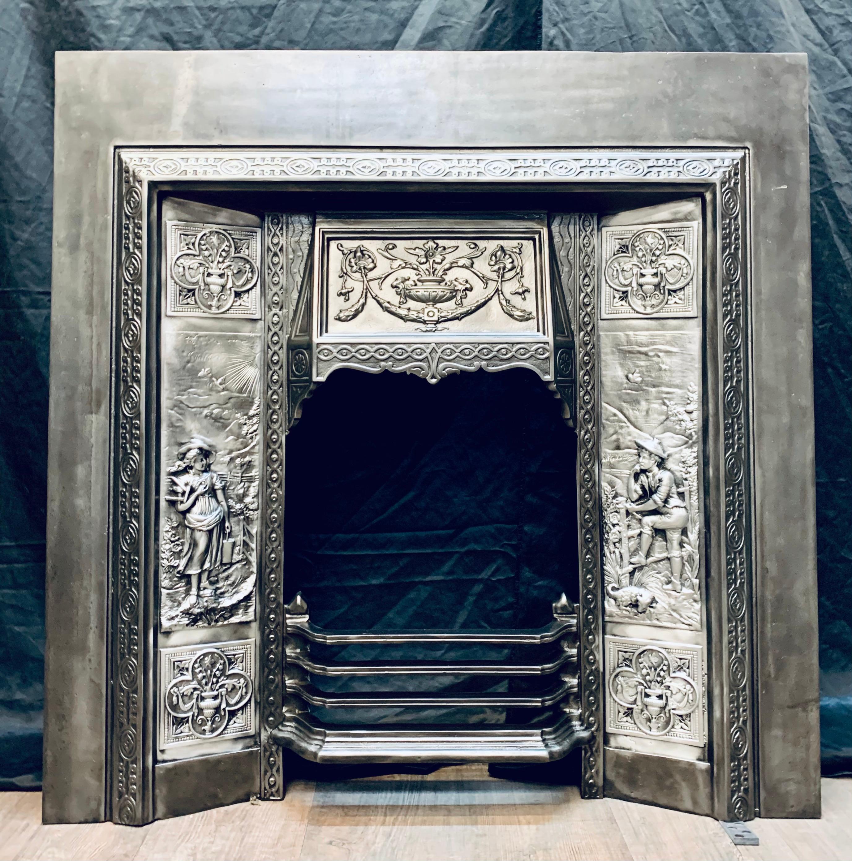 A charming Victorian style polished and graphite waxed cast iron fireplace insert. A generous outer plate, with a raised framed band, a high relief cast hood showing a swag with central urn and griffin heads, flanked by cast panels displaying