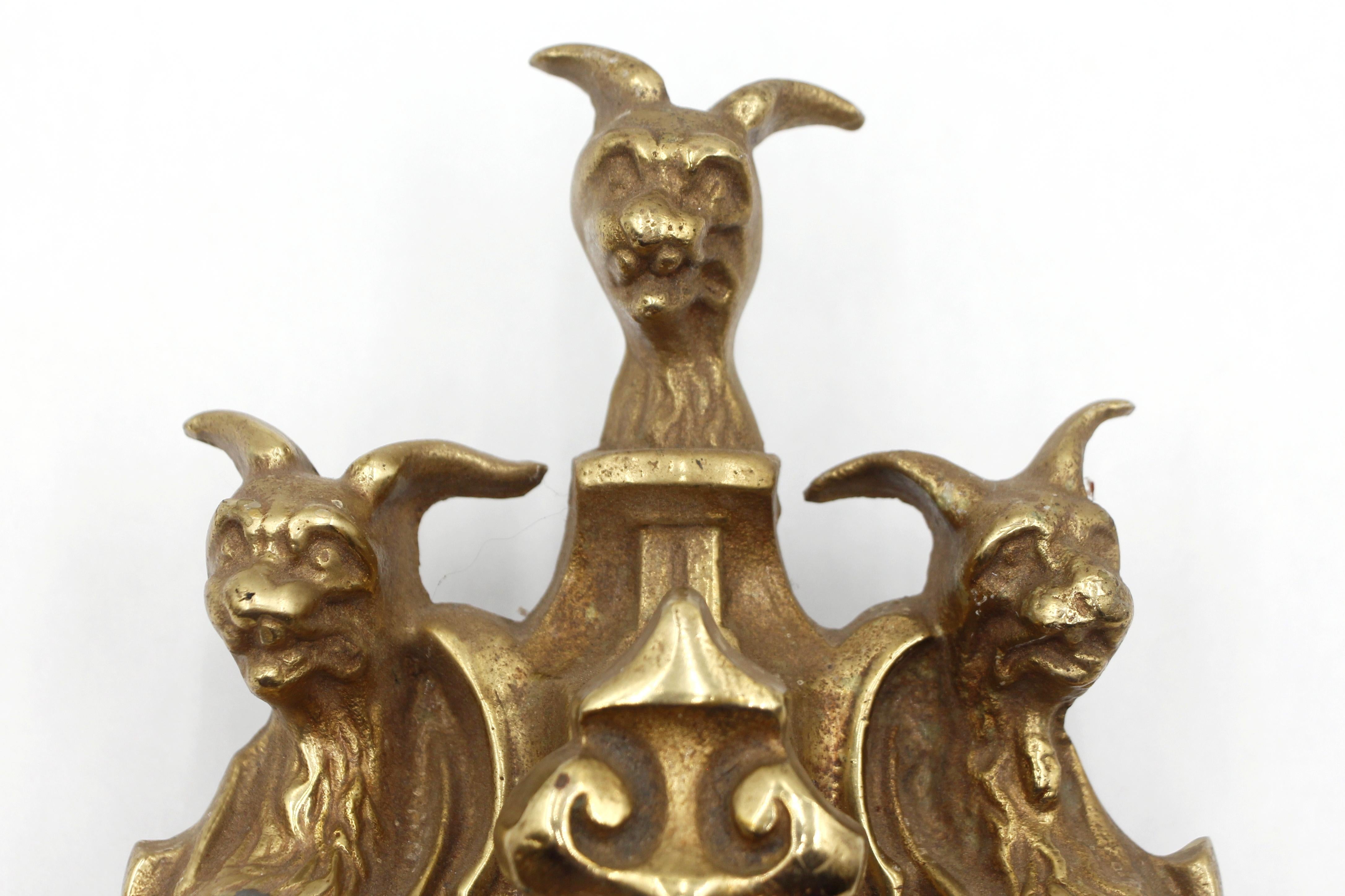 Battente in ottone in stile vittoriano con tre teste di animali stilizzate, che potrebbero essere interpretate come Cerbero. Le viti di montaggio originali non sono disponibili. Buone condizioni con usura superficiale dovuta all'uso precedente.