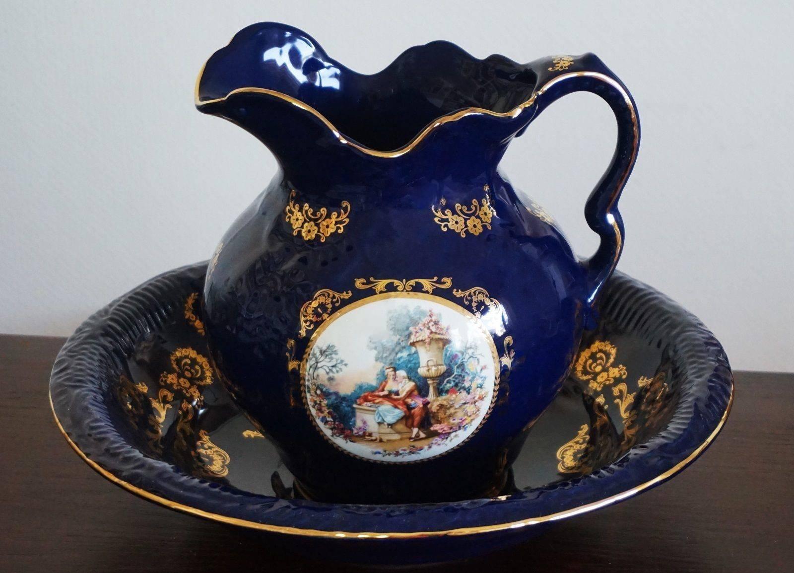 Beautiful Victorian style cobalt blue porcelain wash bowl and pitcher, Portugal, mid-20th century. Hand painted courting scene at both sides and gilded decor, marked.
In excellent condition, color very well preserved (some of the images show white