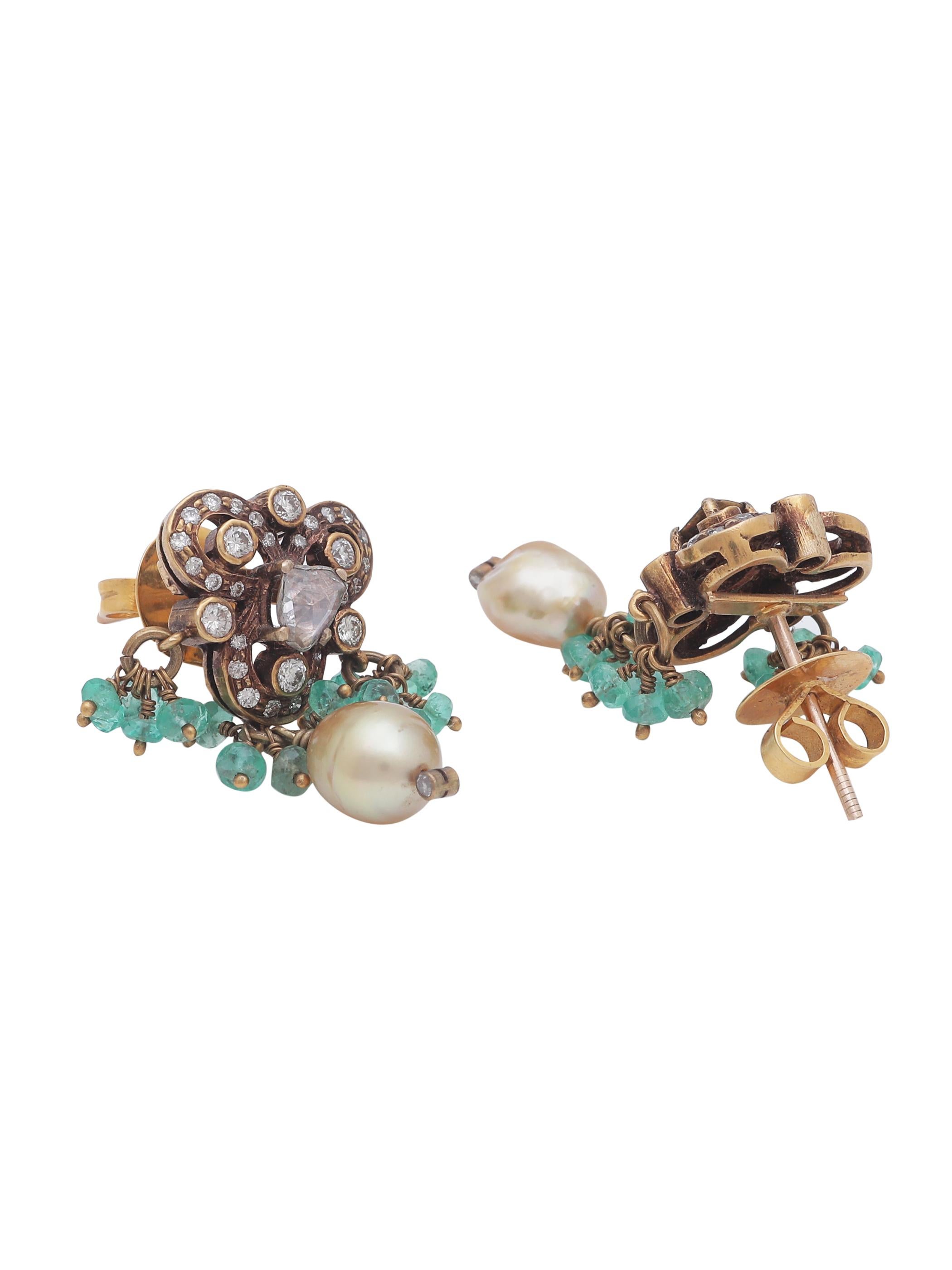 A Victorian style earring pair with diamonds, Emerald beads and a drop shape pearl hanging. The petit and delicate earring is handmade in 18K Gold and has incredible detailing all around. The moving bunch of Emerald facetted beads are strung in Gold