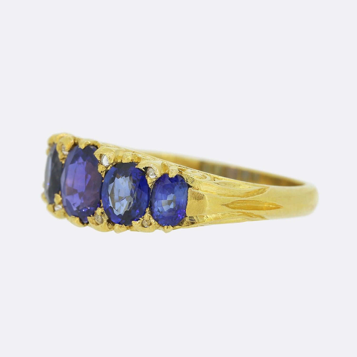 This is a beautiful 18ct yellow gold ring featuring five sensational sapphires spread across the face with two small rose cut diamonds nestled in between each. This piece demonstrates excellent craftsmanship borrowing from the Victorian period with