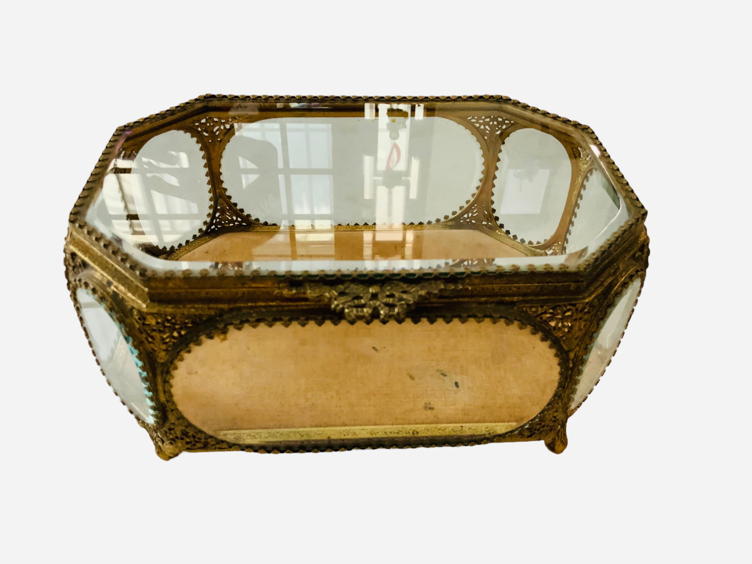This is a large gilt metal octagonal shaped casket/jewelry box. Their beveled glass is framed with a gilt garland of tiny shamrocks and their corners are decorated with a filigree pattern of scrolls, leaves and hearts. The inside floor wood panel of