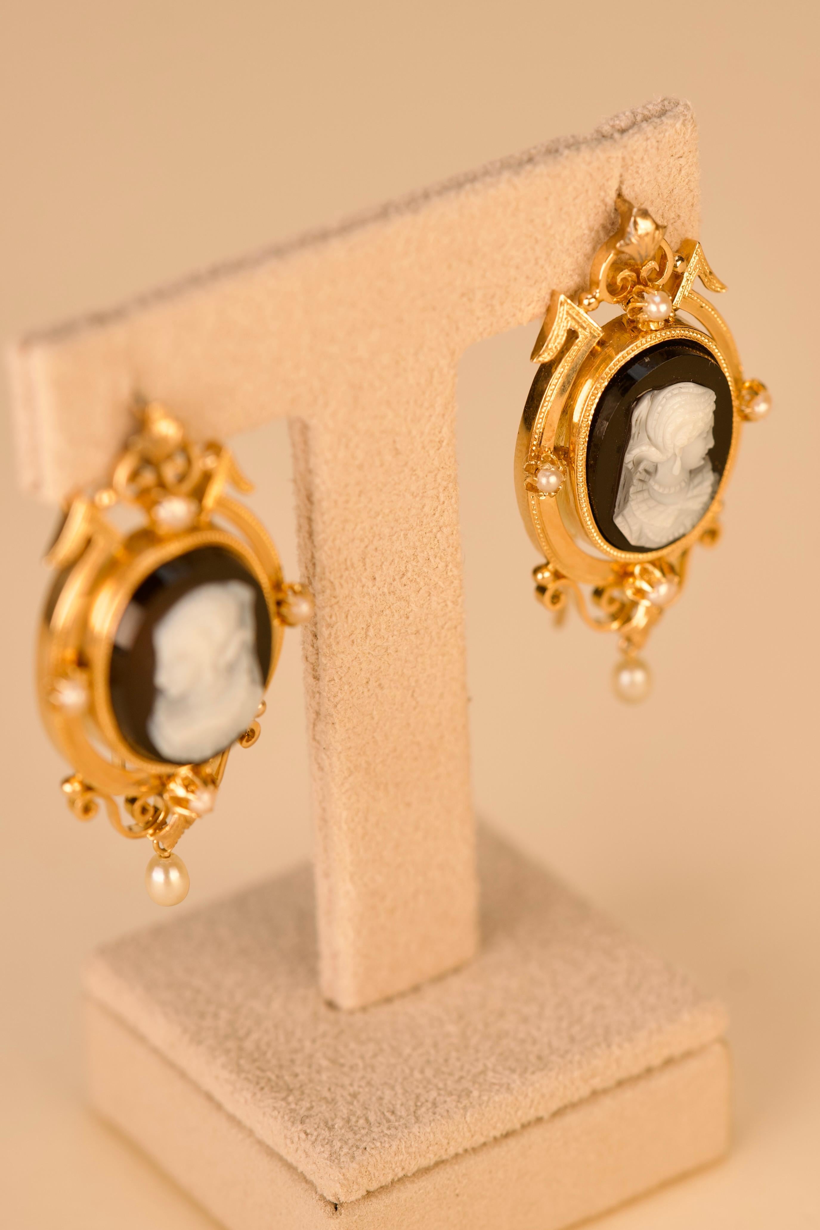 Orecchini in oro rosa 18kt- 750‰, di forma ovale, con cammeo centrale scolpito in agata, raffigurante una figura femminile di profilo con lineamenti delicati e abbigliamento d'epoca. La cornice d'oro è ornata da quattro perle, con un'ulteriore perla
