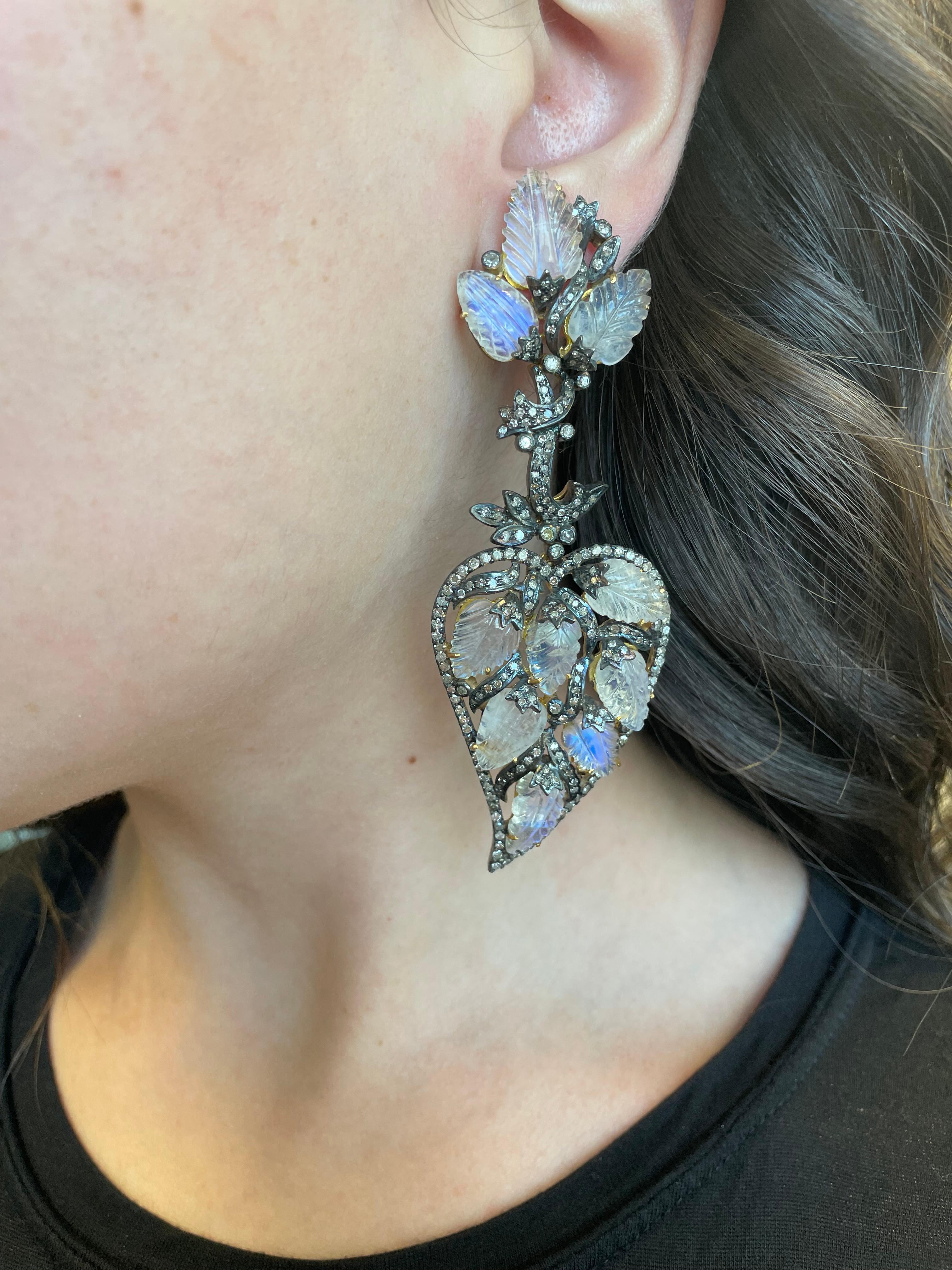 Statement Victorian inspired chandelier earrings.
Approximately 4.80 carats of round cut diamonds, L/M color, and SI clarity. Approximately 42 carats of carved moonstone. Silver and gold.
Accommodated with an up to date appraisal by a GIA G.G. upon