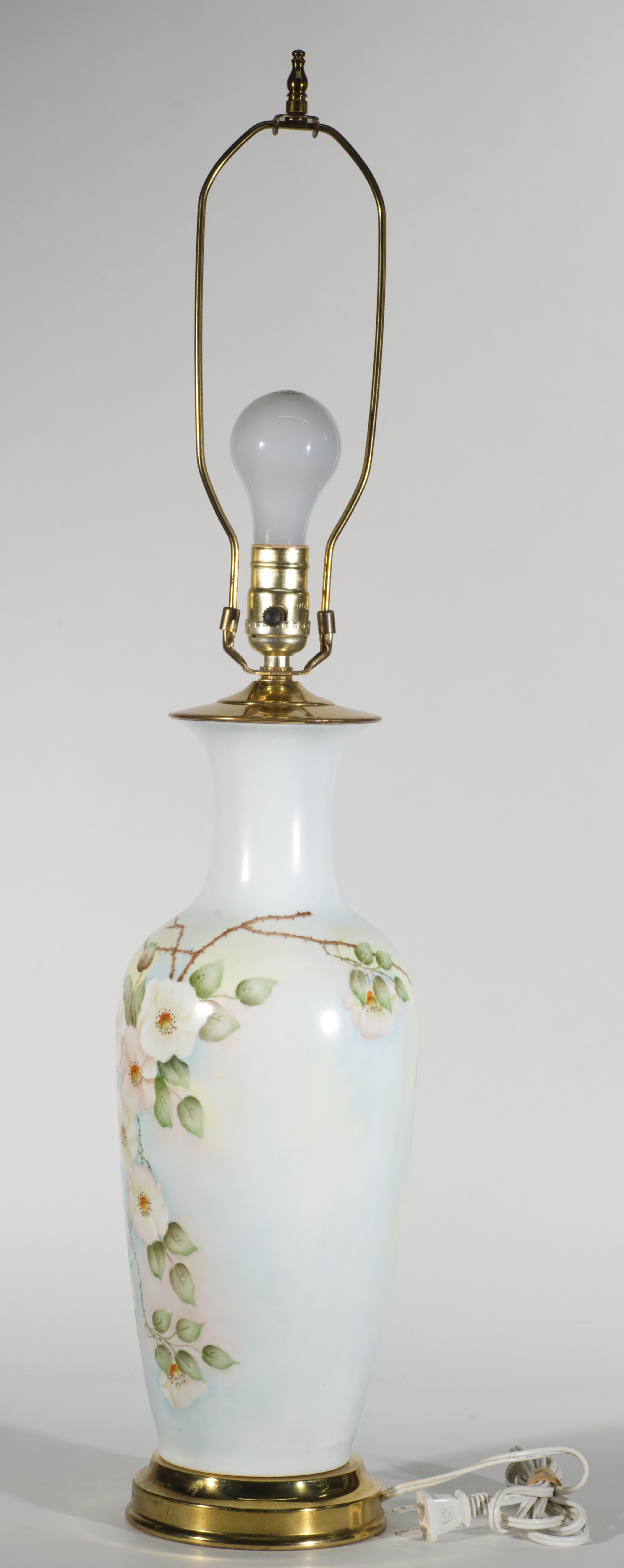 Cette grande lampe de table Vintage présente un corps en forme d'urne avec un charmant décor d'Art Naïf ou Folk Art fortement influencé par les décorations florales de style victorien sur les vases et les lampes.

Le corps de la lampe en porcelaine