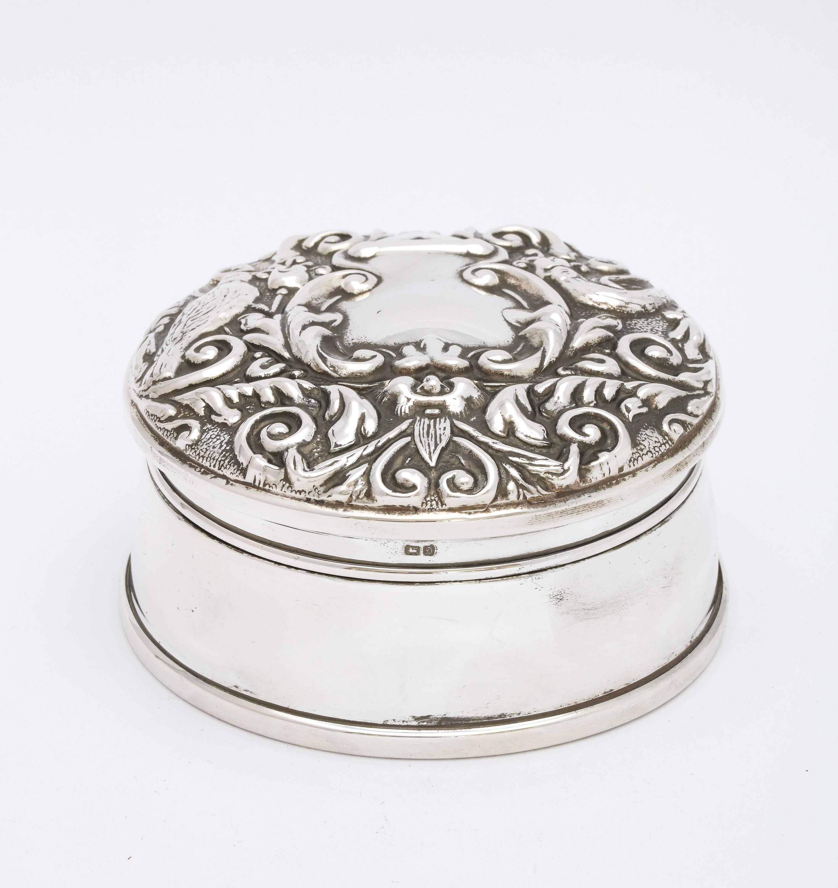 Victorian-style, sterling silver trinkets box with hinged lid, Birmingham, England, year-hallmarked for 1978, Broadway and Company-makers. Lined with navy blue velvet. Underside is covered in leather. Designed with birds, etc. Measures 3 1/2 inches