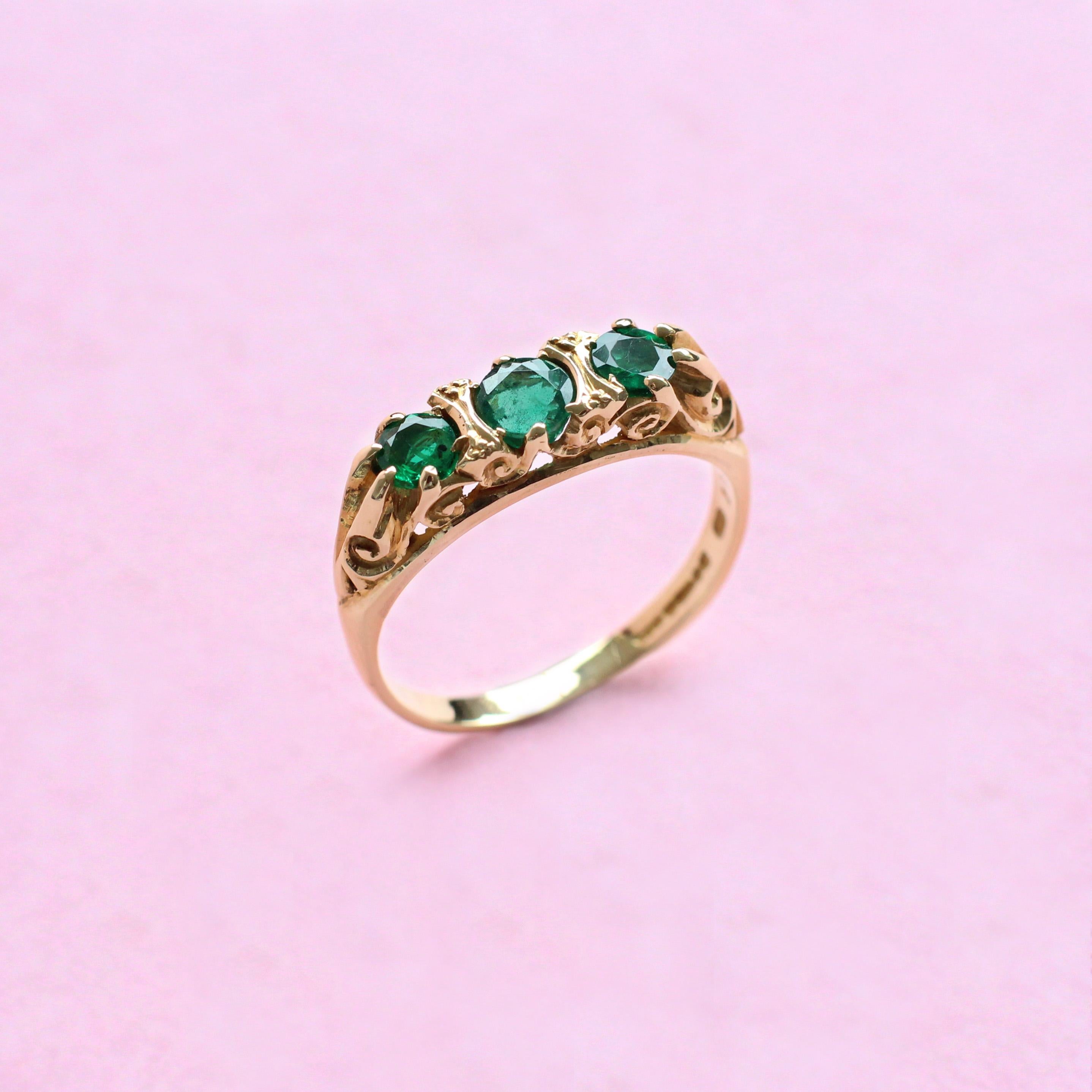 The beauty of this three-stone piece lies in its simplicity. A trio of round cut emeralds in deep, dramatic green are set in a beautiful yellow gold band, whose intricate detail gives it a vintage feel. A unique ring designed in our London atelier