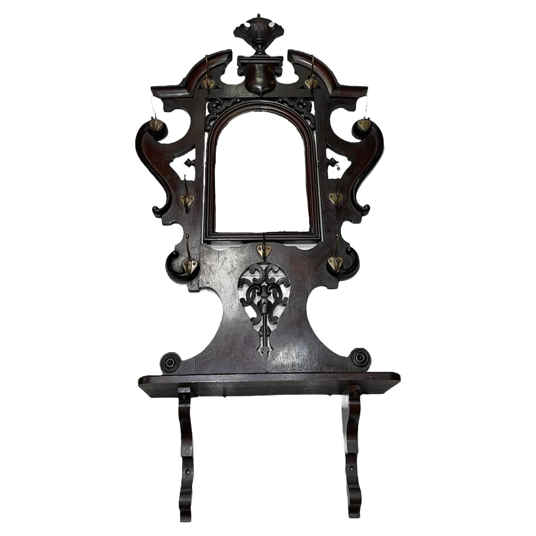 This is a a five feet and four inches tall Victorian style hall wall wood mount mirror and coat, hat, scarf and /or umbrella rack made in Puerto Rico. It depicts a semilunar shaped mirror framed with dark brown wood. Above the mirror, there is a