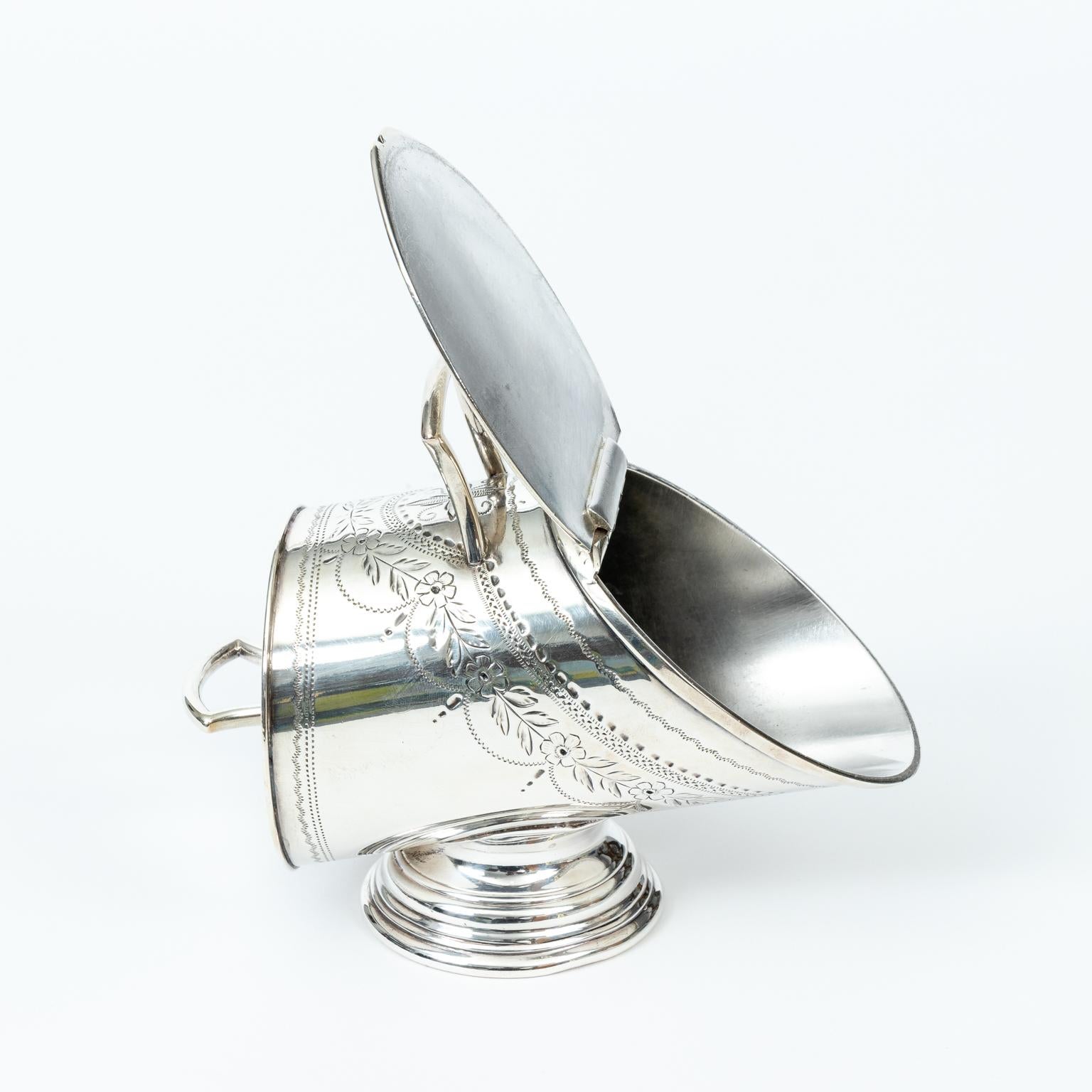 English Victorian sugar scuttle in silver plate, circa 1890s. The piece is detailed with foliage motifs throughout. Please note of wear consistent with age. The piece has been replated. Made in England.