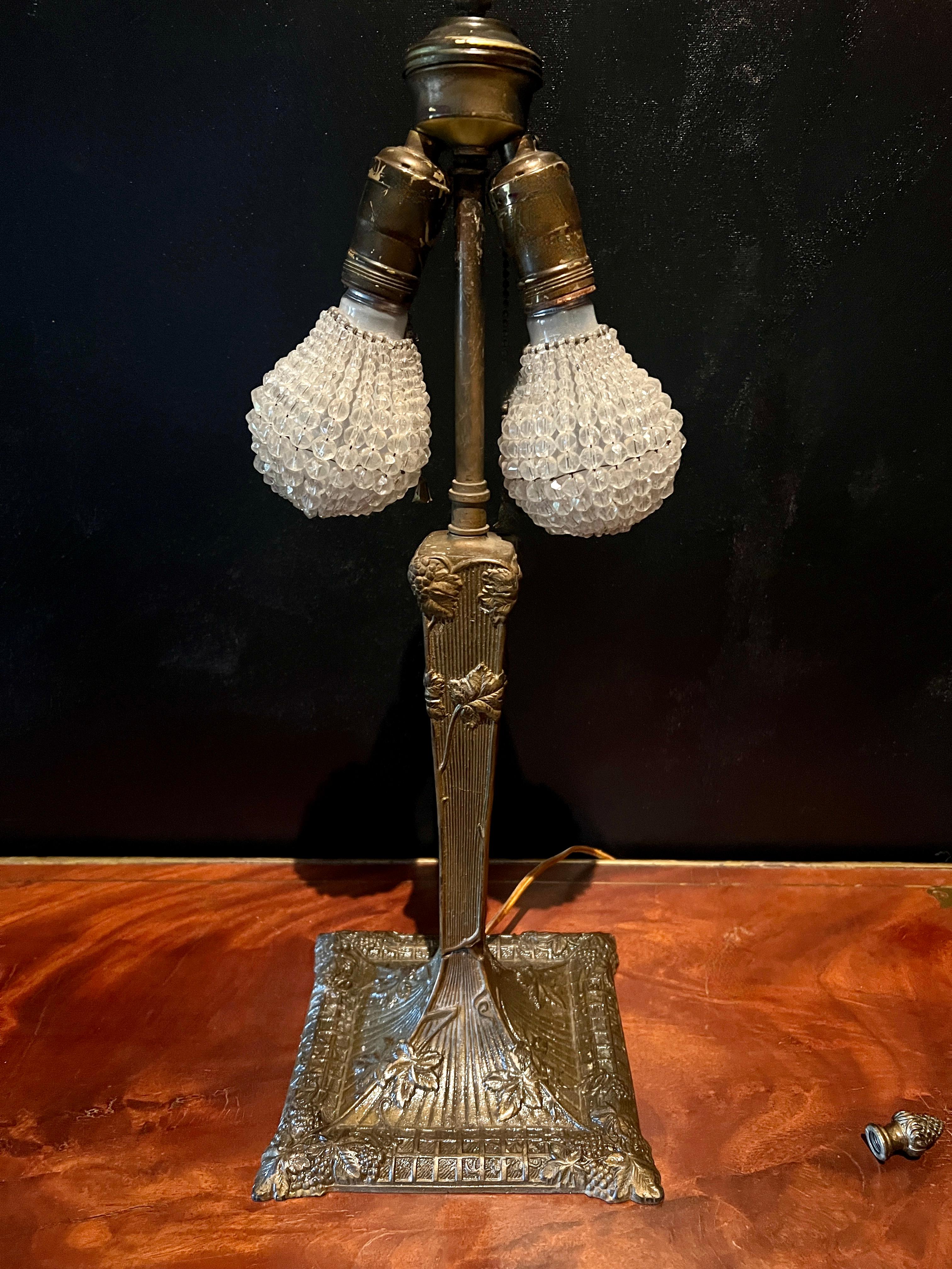 A wonderful Victorian Bronze table lamp in the style of Tiffany.  The lamp base is beautifully detailed with flowers and vines, leading to a large dome shade which is very details with a filagree trim and inset glass disks and beads of different