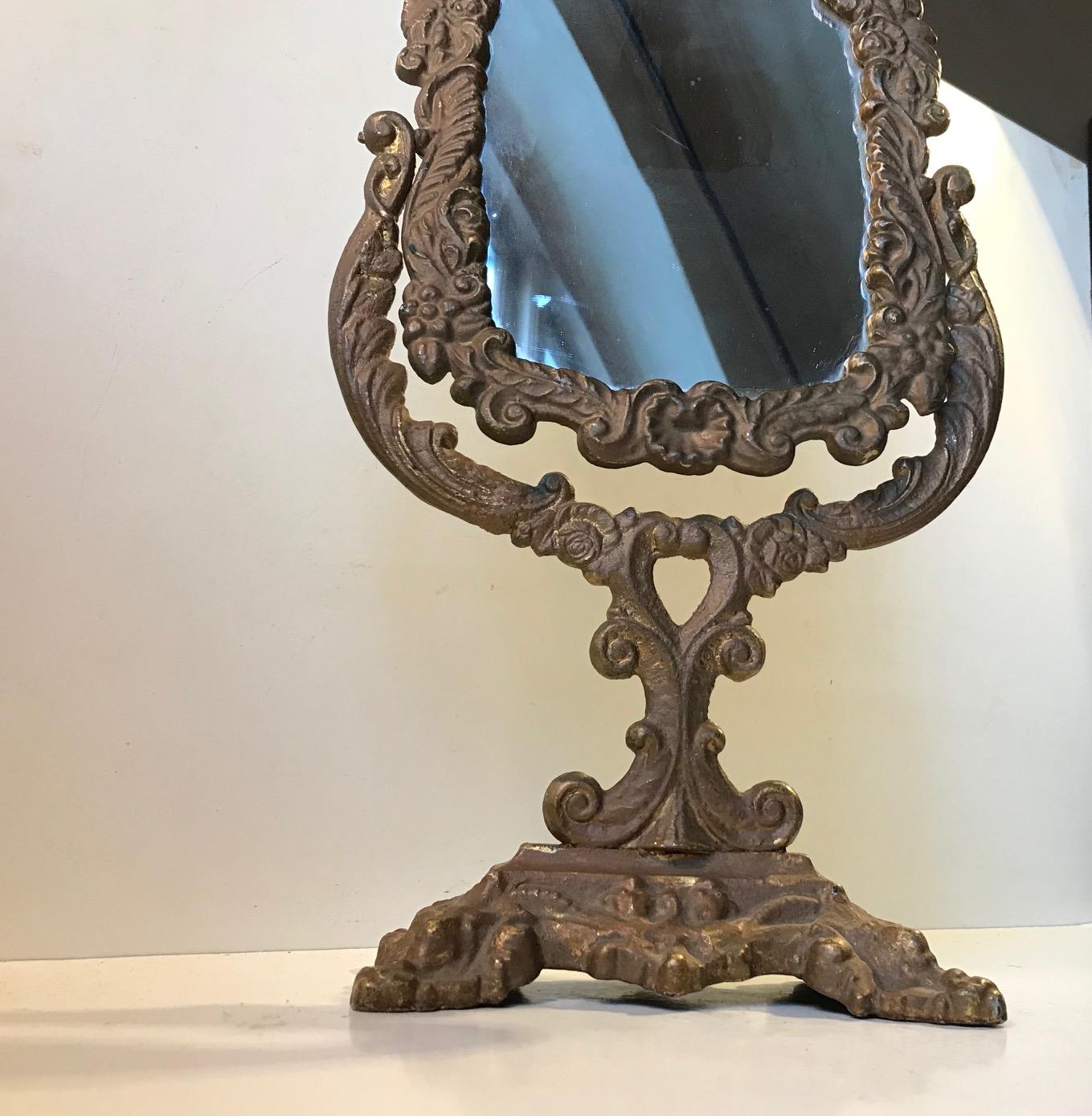 Late Victorian vanity/table mirror/ make-up mirror in cast iron. It has been painted a long time ago in a color that mimics patinated bronze. Possibly an original paint job. It has a few scuffs here and there giving it a shabby chic look. It rotates