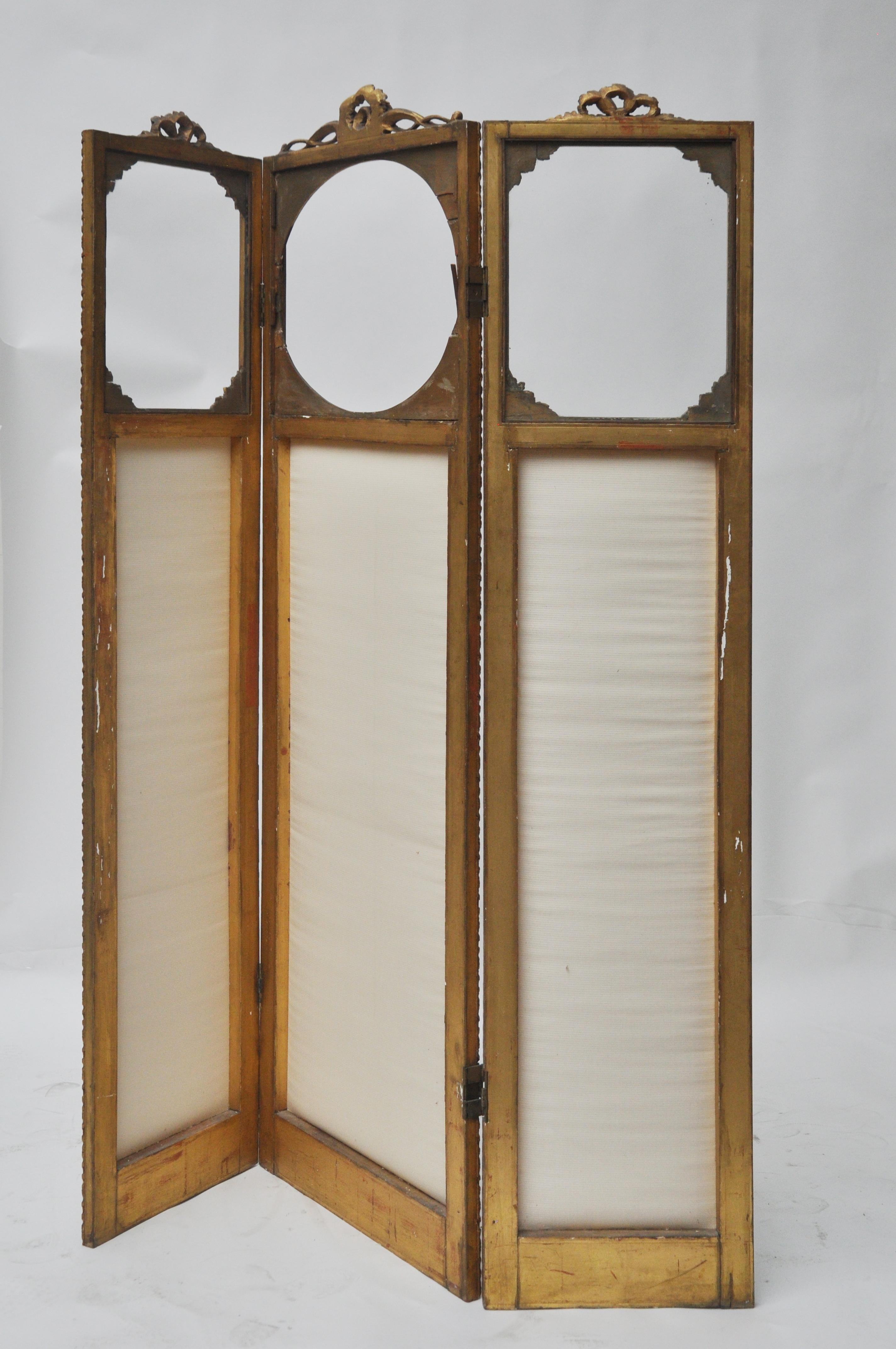 Victorian screen has hinges that bend in both directions. The fabric is off-white. The top of each panel has a piece of glass so that you can see through the top of the screen. The tops wooden pieces are carved and fragile. The middle panel is