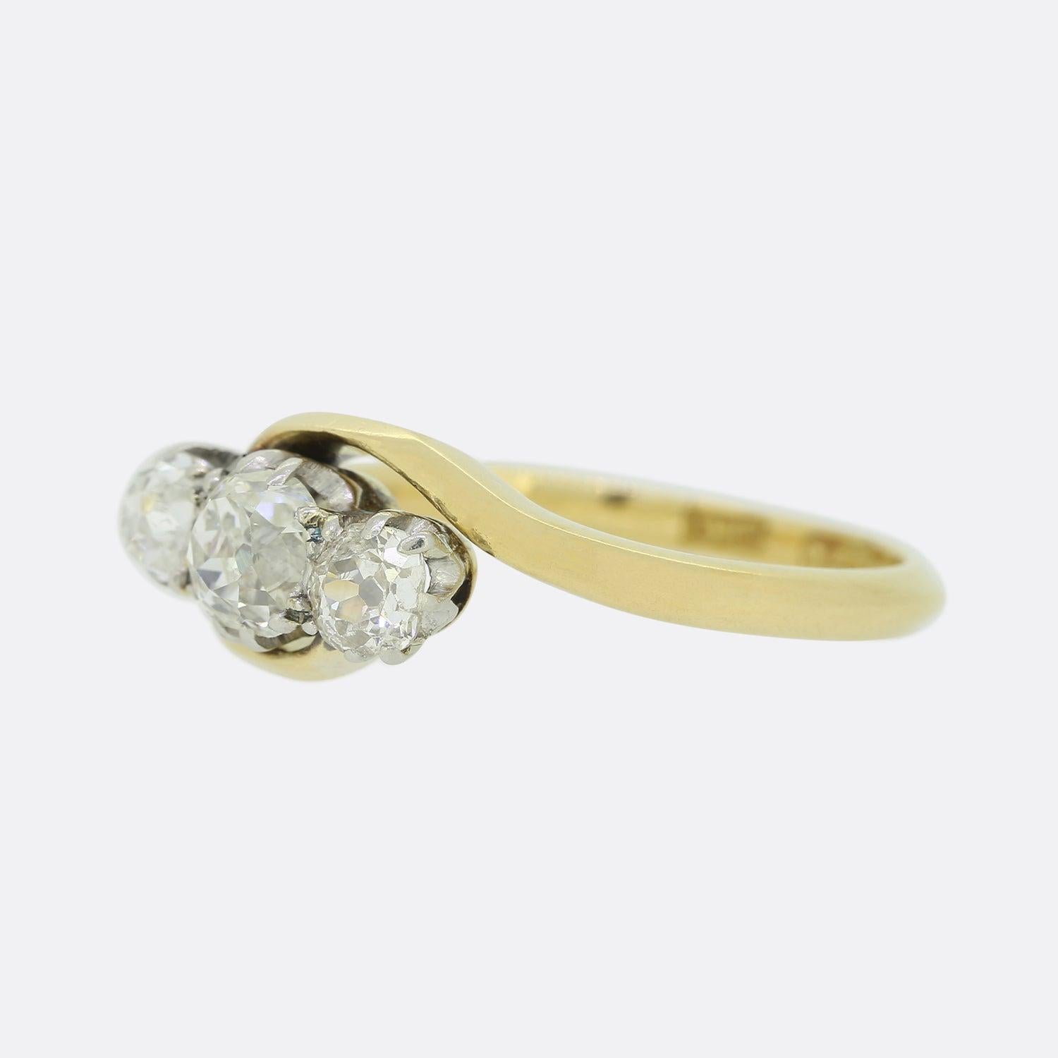 Il s'agit d'une bague victorienne en or jaune 18ct et en platine à trois pierres torsadées. La bague présente trois diamants de taille ancienne sertis en platine au centre de deux élégants anneaux croisés. Les diamants sont bien assortis en termes