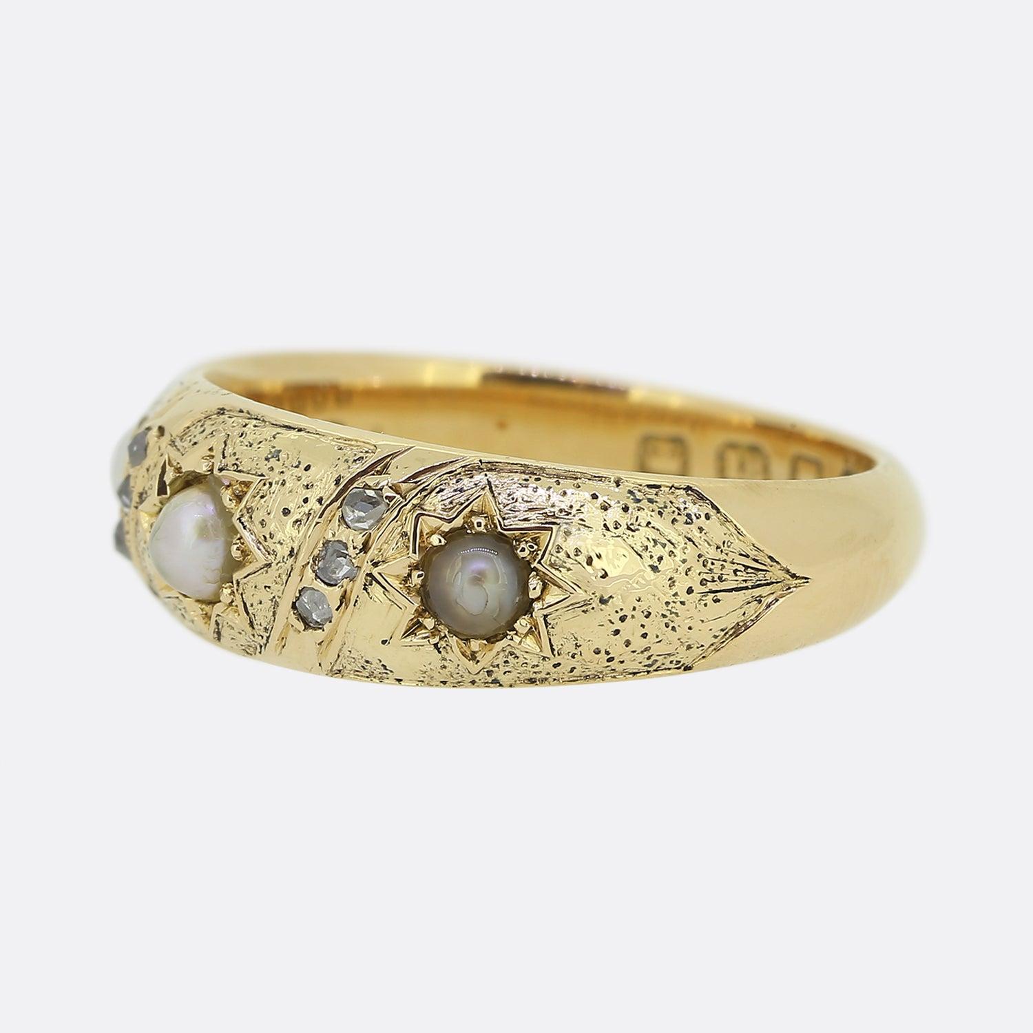 Here we have an 18ct yellow gold three-stone pearl and diamond ring from the Victorian era. The piece showcases a stylish textured backdrop which plays host to a trio of star-burst set natural pearls; each of which is divided by a trio of vertically