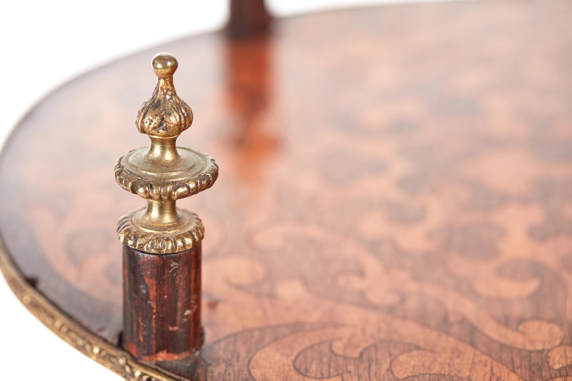 This is a 19th century Victorian antique three tier oval inlaid stand. The three tiers are beautifully and expertly inlaid with kingwood and satinwood with pretty brass band edges. It is supported by four shaped legs with charming ornate brass