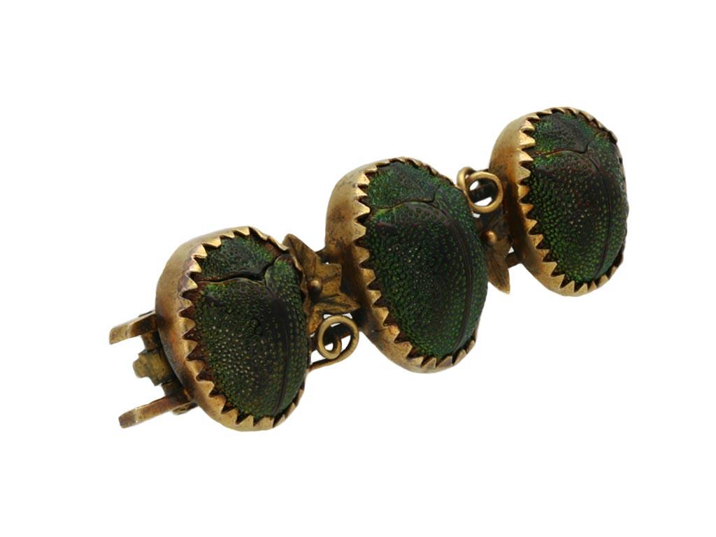 Victorian tortoise beetle brooch. Set horizontally with three iridescent Brazilian tortoise leaf beetles graduating in size from the centre in closed back claw settings, to a novelty beetle brooch featuring two ivy leaf motifs with a gold bead and