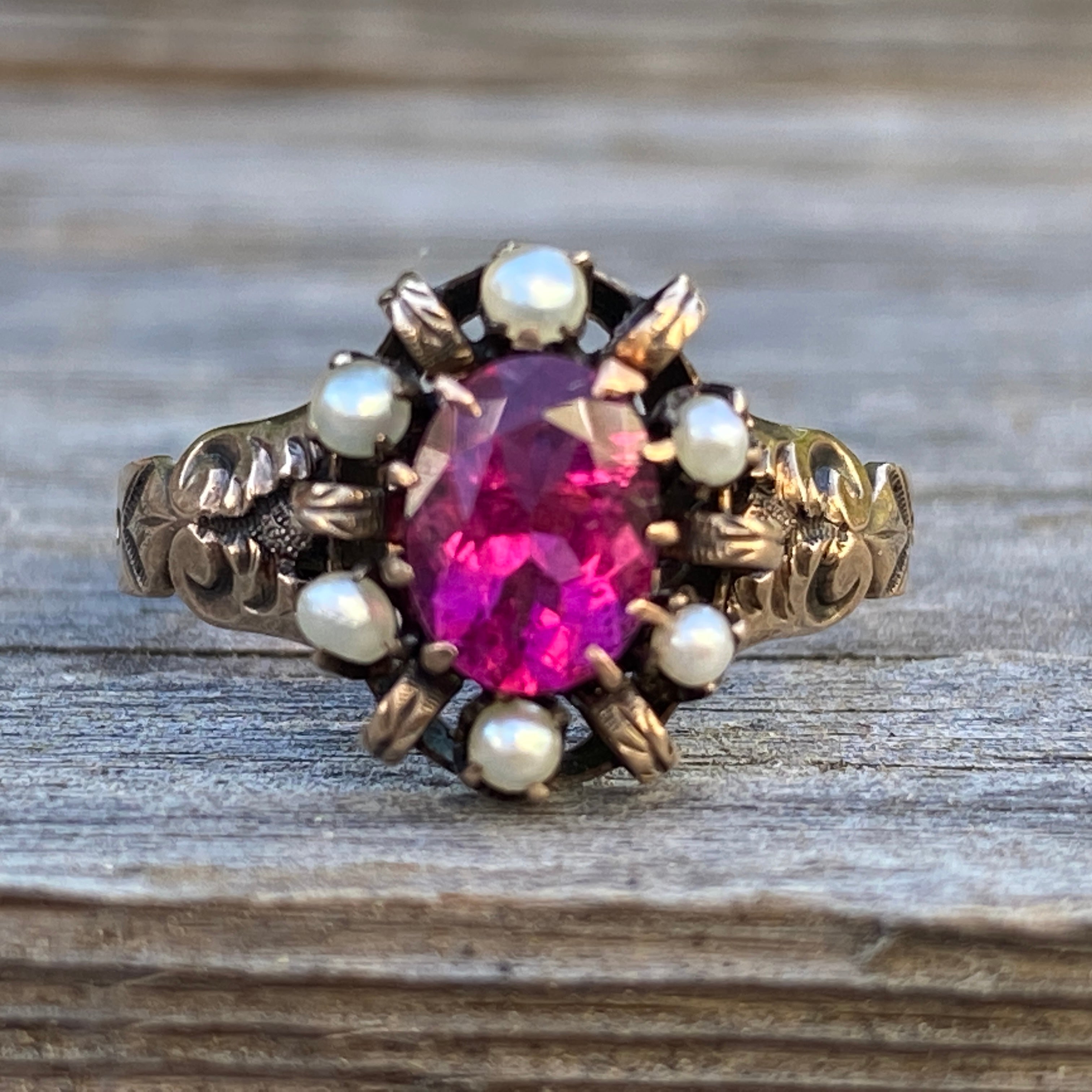 Details:
Sweet Pink Tourmaline and seed pearls set in 14K yellow gold. The tourmaline is a vibrant rich pink color. The Victorian setting has a sweet scroll pattern on the shoulders and a lovely claw setting. This sweet ring has engraving with the