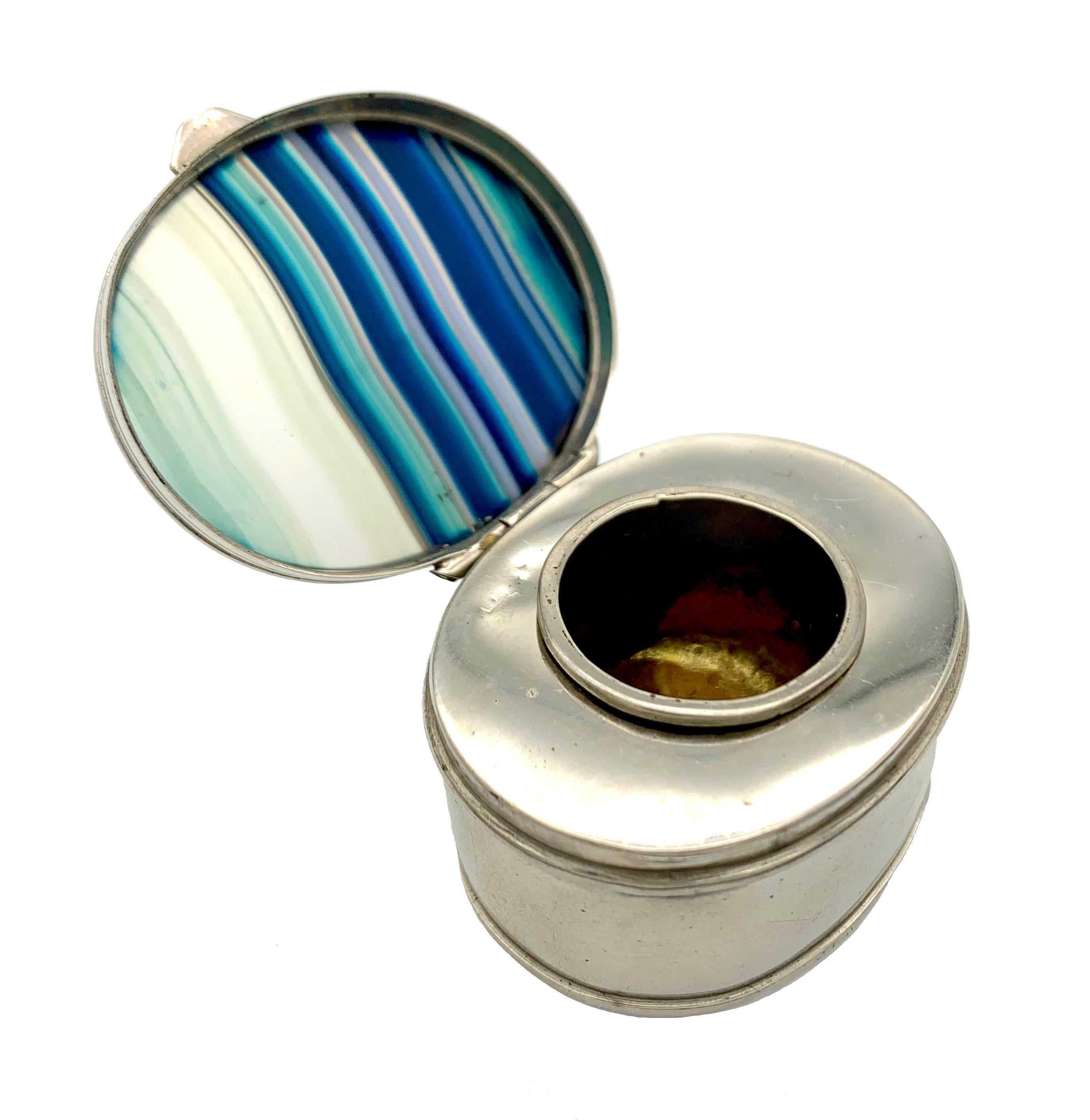 This little elegant travelling inkwell is made out of plated silver. The lid and the bottom of the box are set with slices of agate dyed blue.