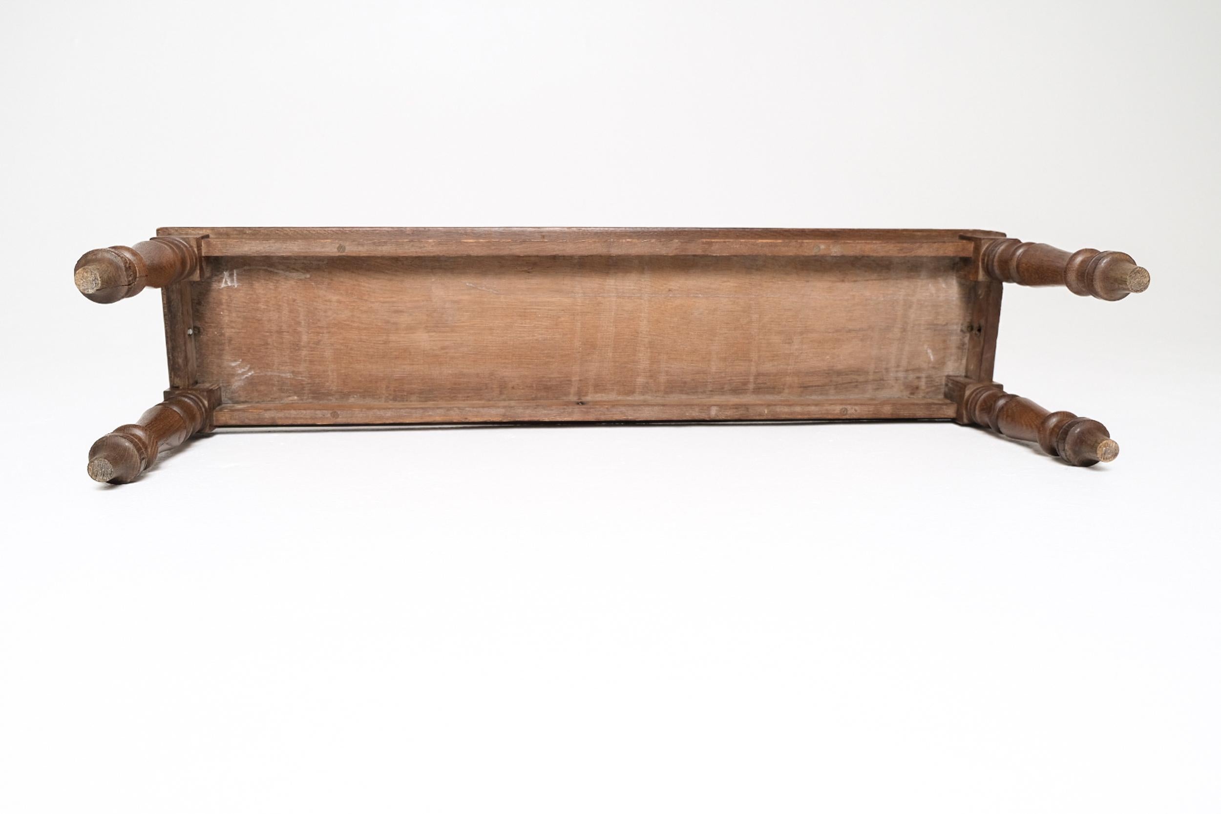 A charming and well-proportioned Victorian oak hall bench, crafted in England in the late 19th century. The bench features a solid oak plank seat framed by decorative scroll end supports and rests on classic turned legs with a tapered foot. Compact