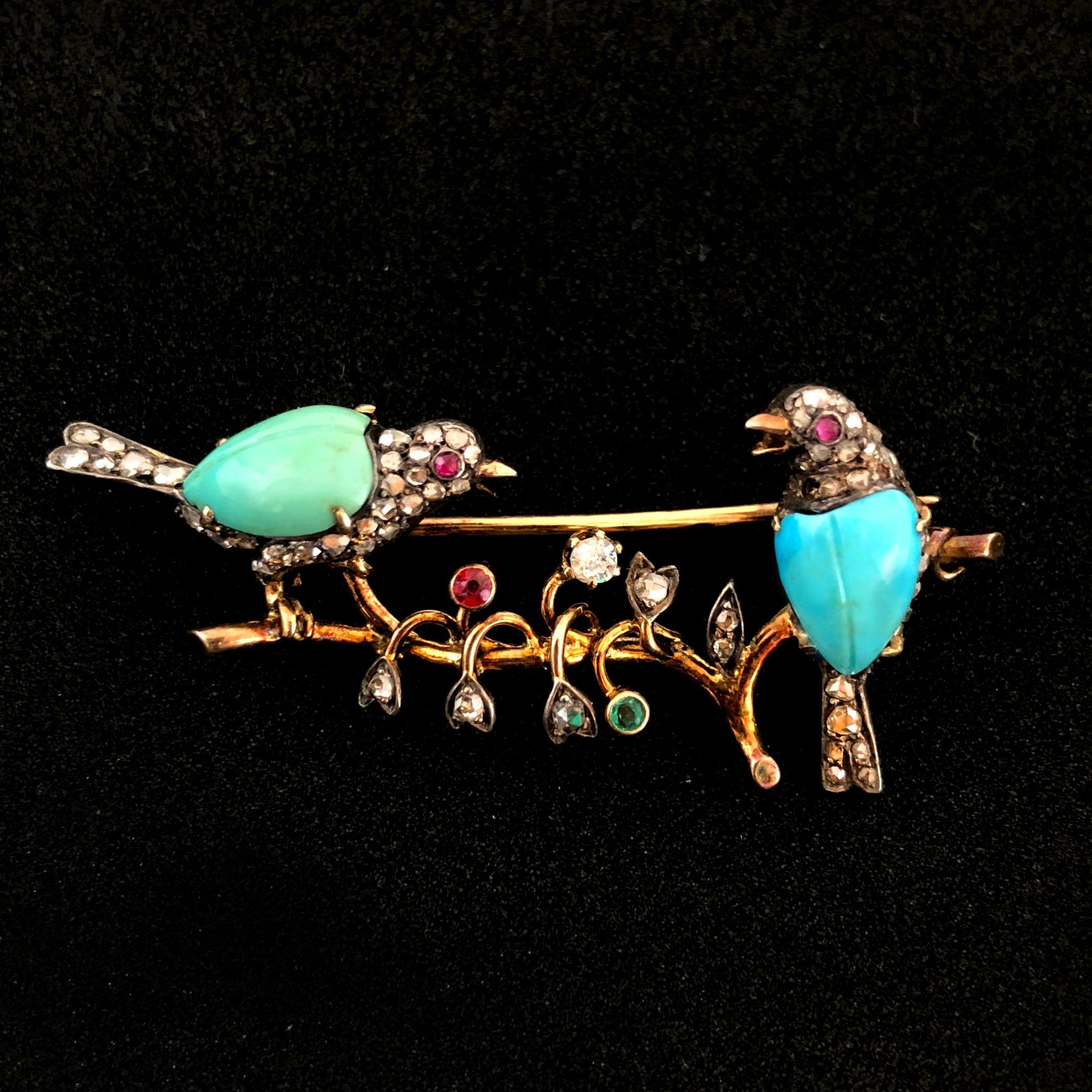 A very lovely Victorian brooch depicting a nest with two birds and flowers. The birds are studded with ruby eyes, diamond and turqouise and the flowers are studded with diamonds and a ruby and an emerald. 
- with French 18k gold stamp mark