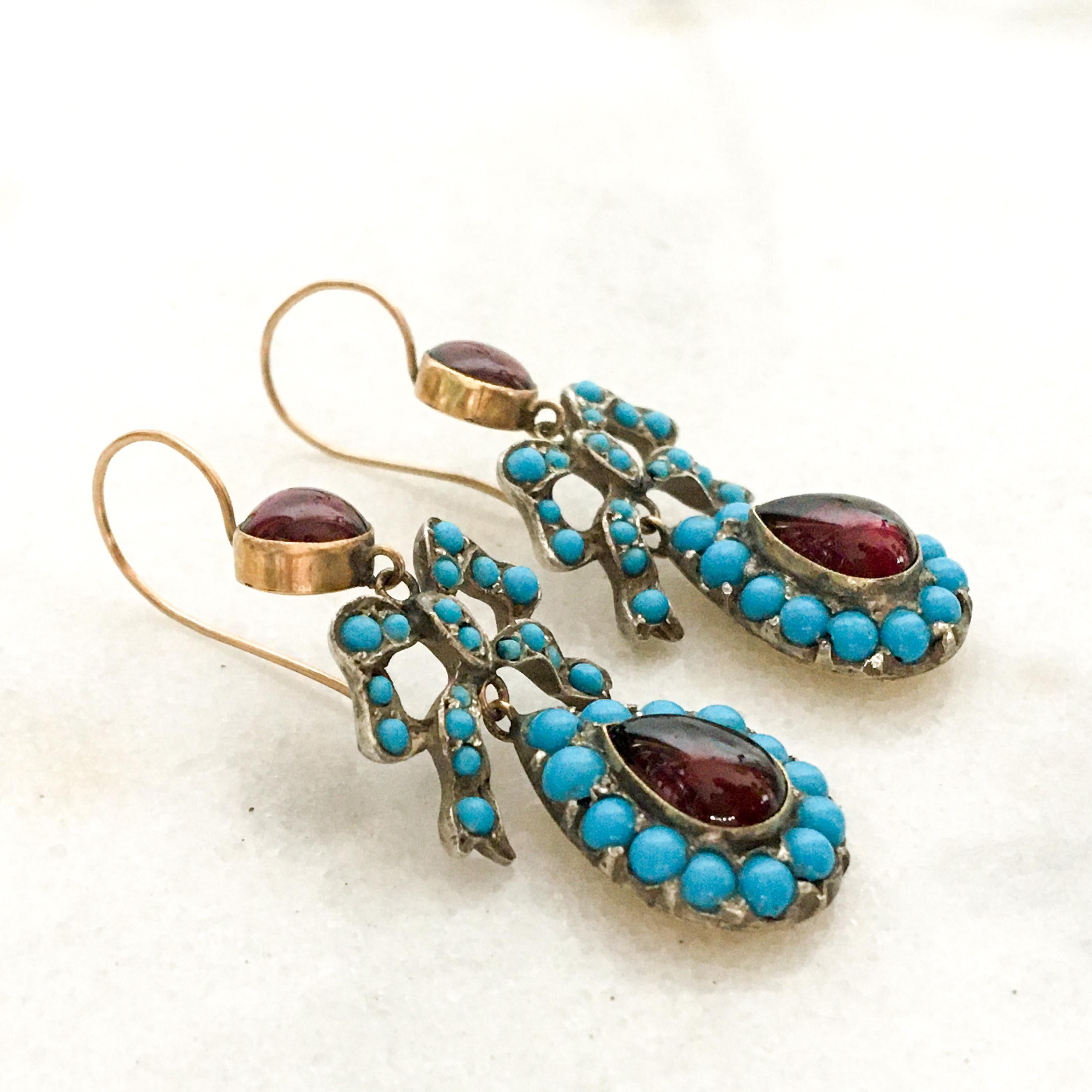 Pair of turquoise garnet bow earrings crafted with gold and silver, dating from the Late Victorian era. Each earring is set with a cluster of turquoise cabochons in the shape of a bow, below the bow a pear-shaped dropper with pave set turquoise