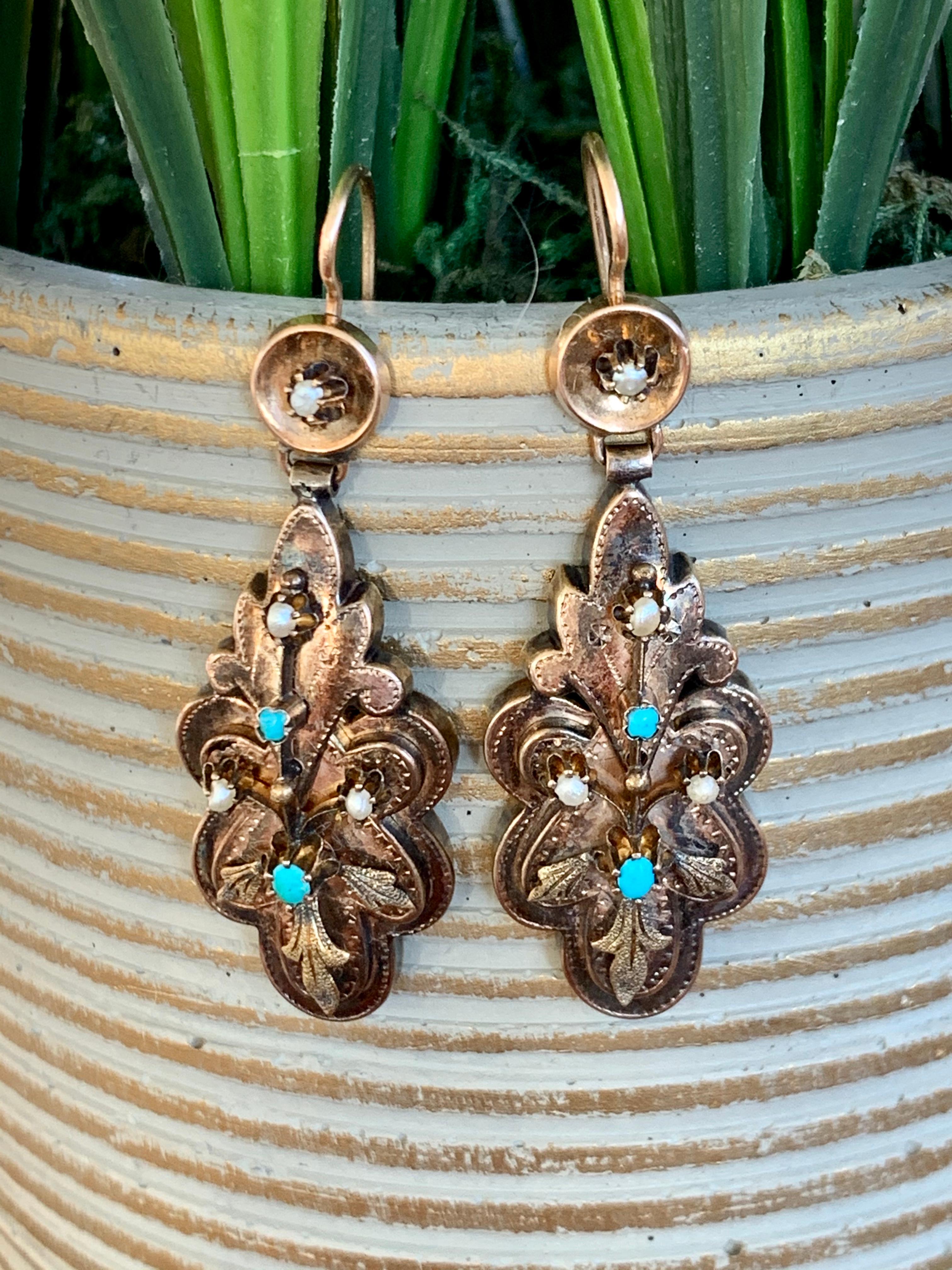 These Victorian earrings feature two Turquoise stones and three Pearls in each earring.  They sit amongst the beautiful intricate Gold workmanship which is seen in Victorian jewelry.

A shepherd's hook ear wire holds the earrings in place. 

Size: