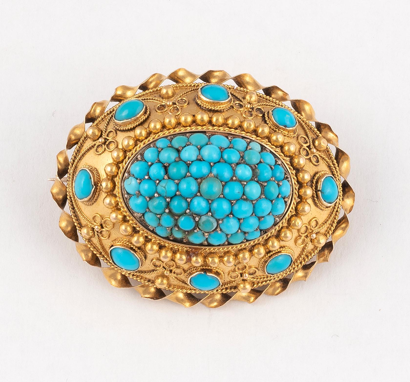 The brooch of oval form, set with a cluster of circular cabochon-cut turquoises, the surround with wirework detailing and further oval cabochon-cut turquoises, with glazed compartment to the reverse.
Brooch width 36mm