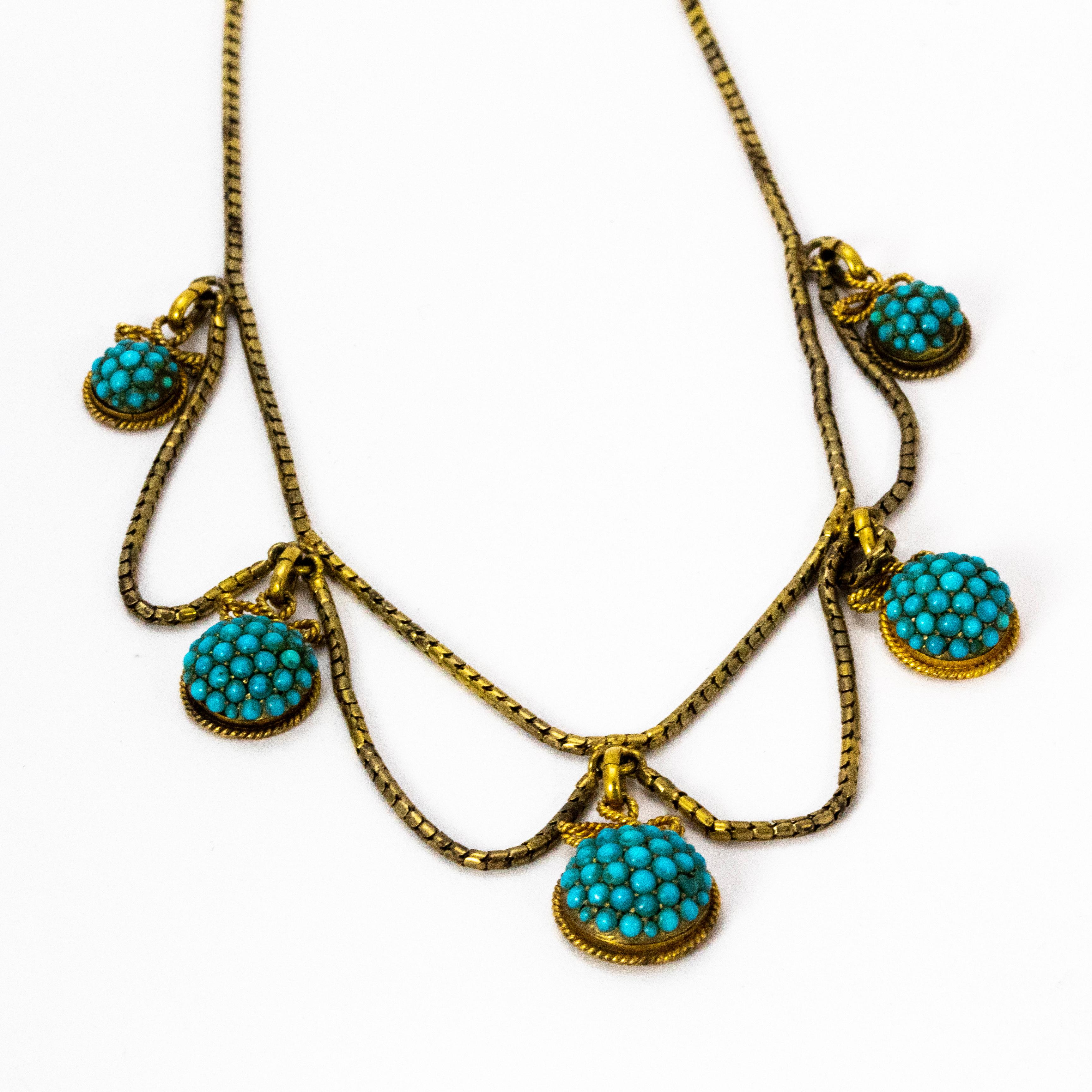 A superb Victorian necklace. On the fine cylindrical link chain hang five gold domes set with exquisite turquoise clusters. Atop each of these graduated clusters is a great rope bow design linking them to the chain. Modelled in 18 karat yellow