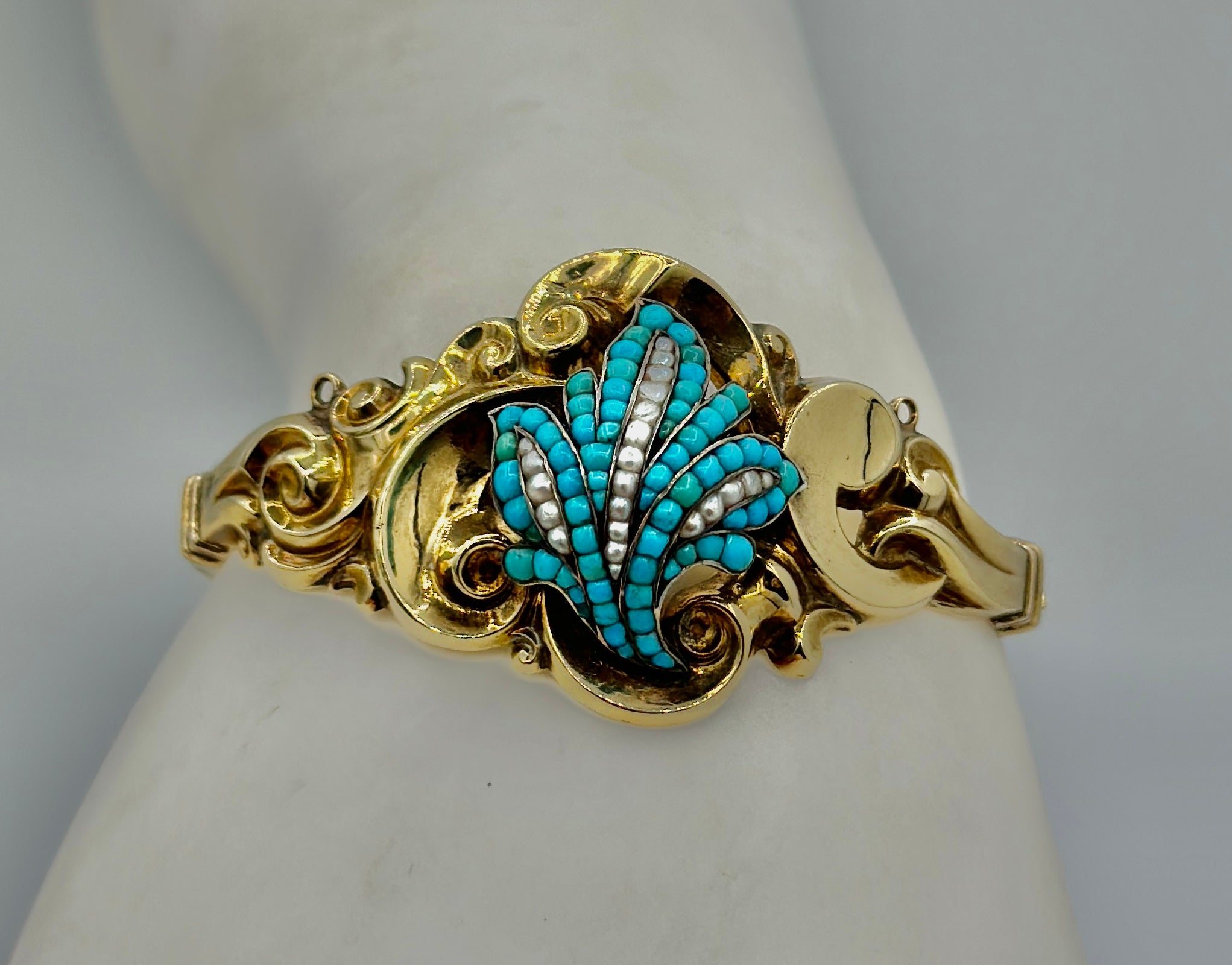 This is a gorgeous antique Victorian Turquoise, Pearl and Gold Bangle Bracelet.   The hinged bangle bracelet has elegant repoussé scroll and leaf motifs, set with turquoise cabochons and seed pearls.  The interior circumference is 6 3/8 inches and