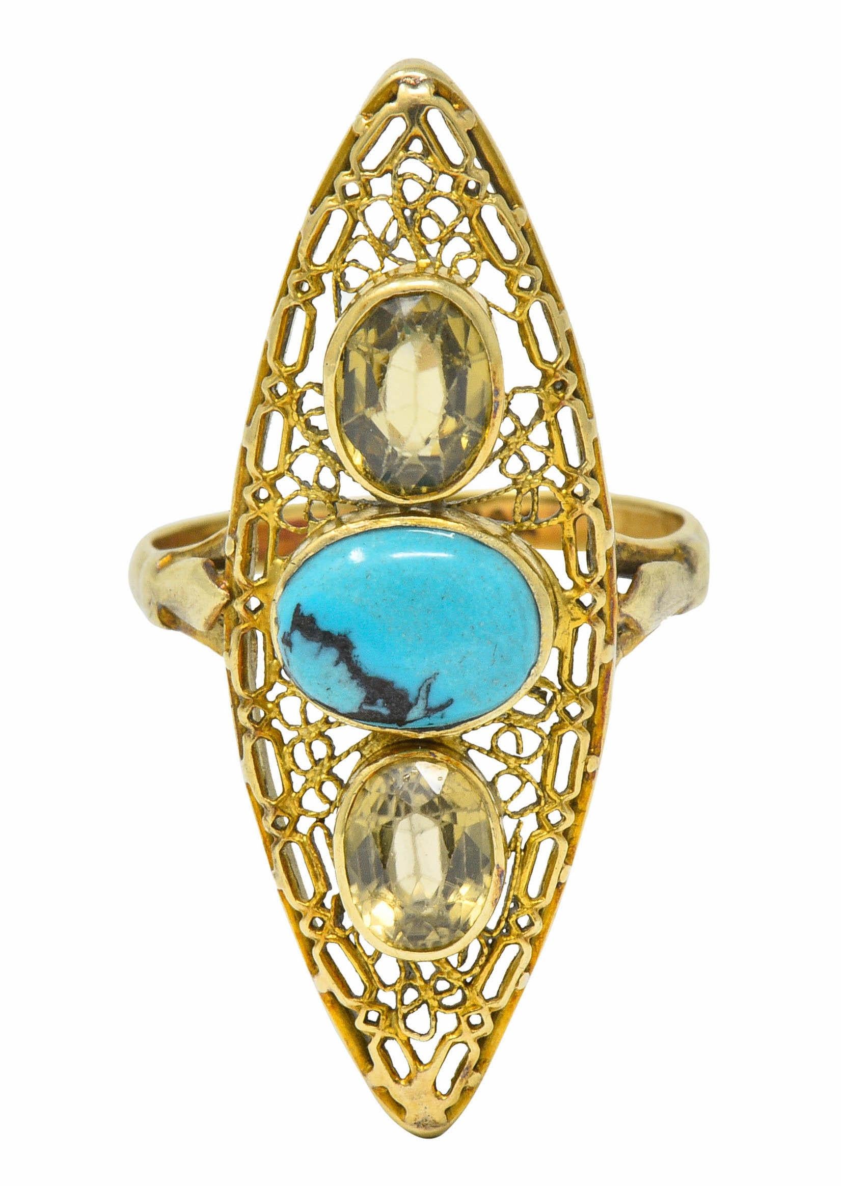 Intricately pierced navette shaped mounting with stylized shoulders

Centering an oval turquoise cabochon measuring approximately 8.0 x 6.0 mm; robin's egg blue color with black matrix

Flanked North and South by oval cut zircon measuring