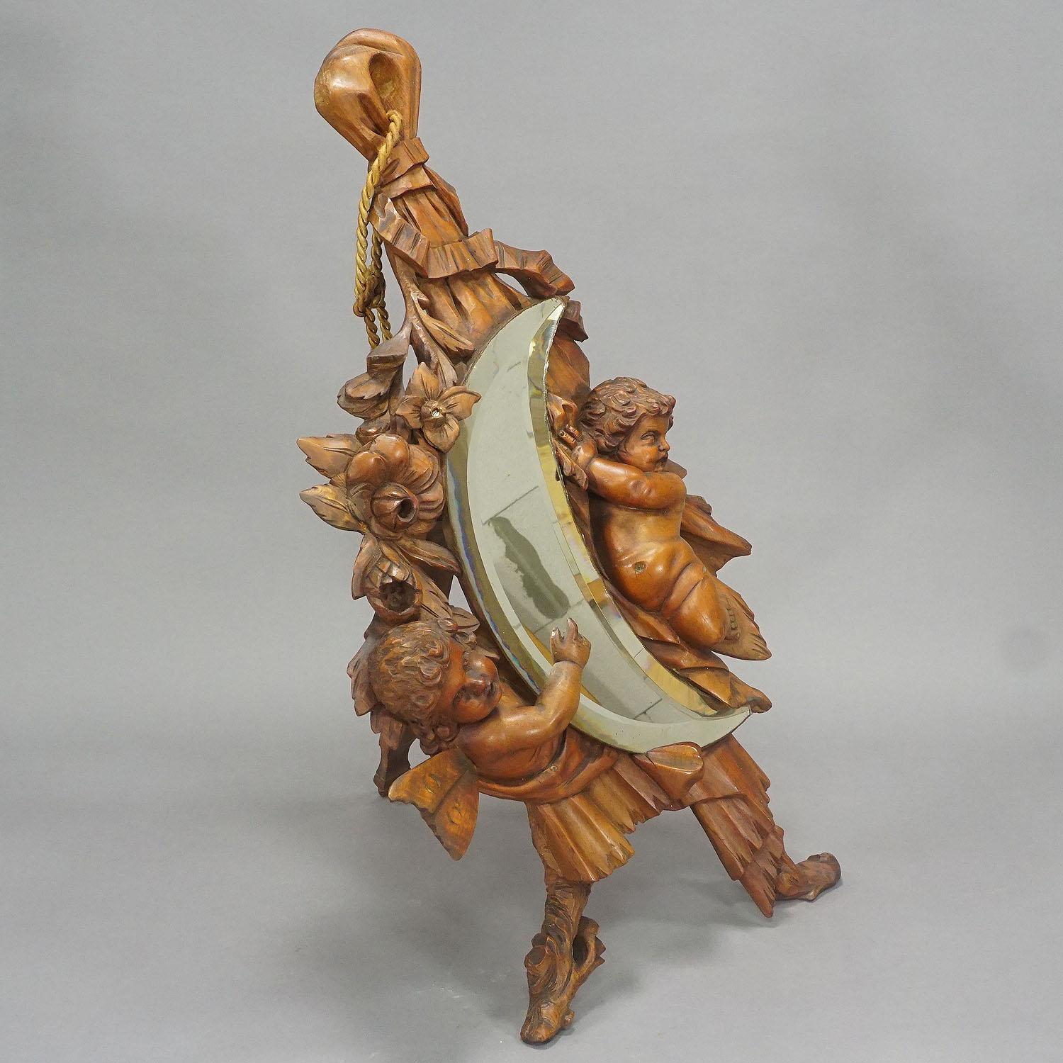 A wooden vanity mirror decorated with elaborate carved cherubs and flowers. Handcarved in Italy or France around 1900. With original antique mirror in good condition. Can be used hanging on the wall or as cheval mirror.

Measures: Width: 12.99