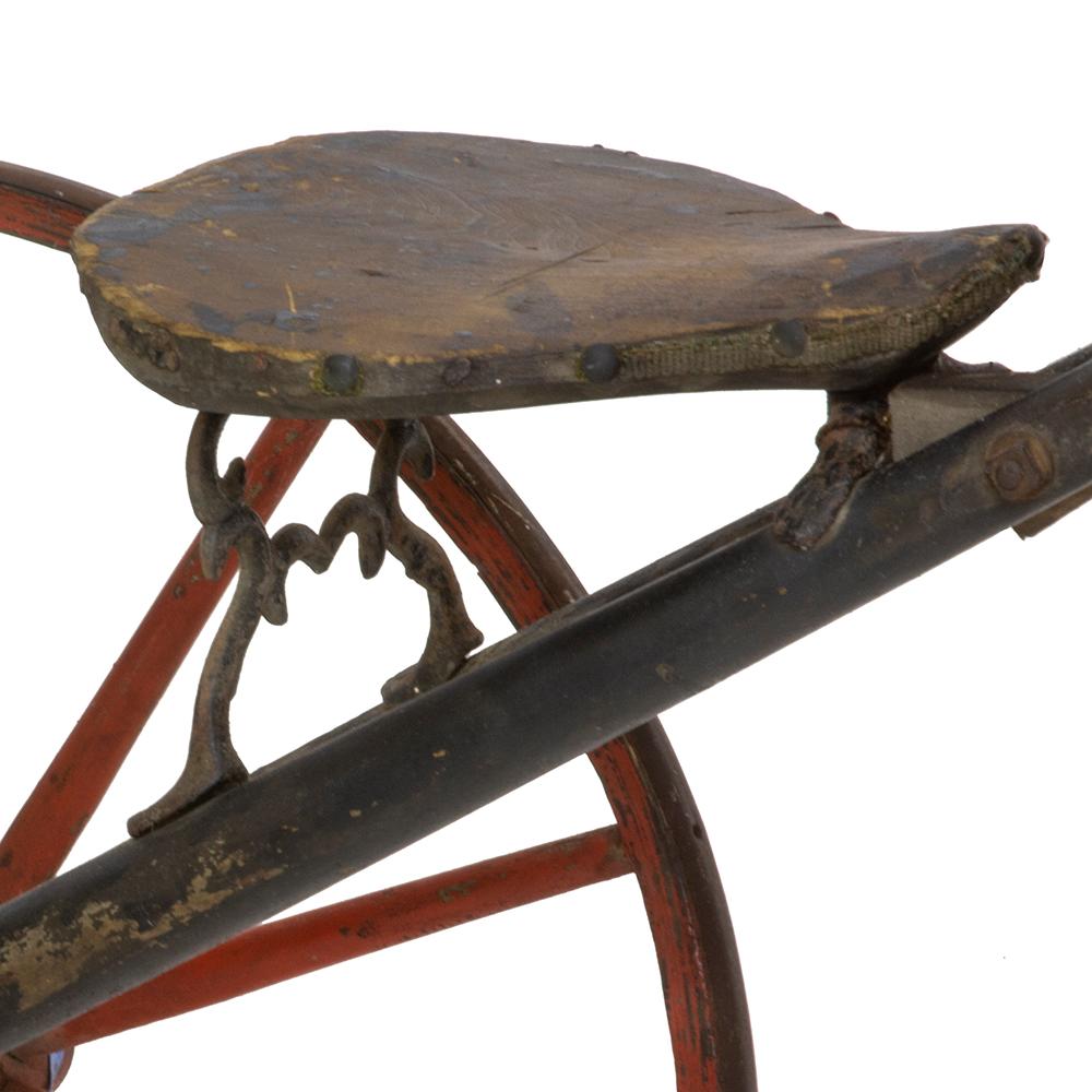 The term velocipede refers to any class of human-powered vehicle with one or more wheels such as bicycles and tricycles. This circa 1870s example is a tricycle style that has classic red accents on a wood frame. It also maintained the original