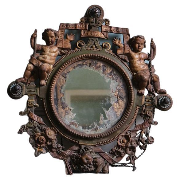 Victorian wall mirror adorned with putti.

Polychromed cast iron with original glass plate. This Victorian cast iron wall mirror is presented with a pair of cherubs who flank the outer side, along with a decorative scheme of floral motifs and