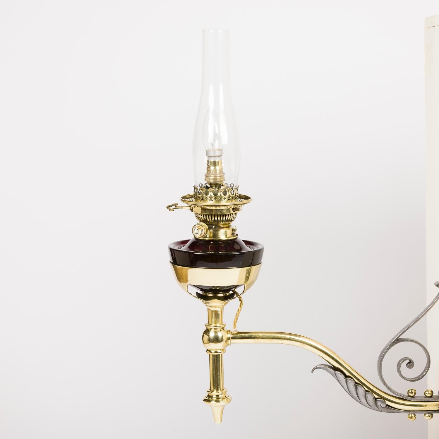 A Victorian wall mounted oil lamp, converted to electricity, with purple glass and brass lamp, brass and iron bracket, with a clear glass chimney. Circa 1890.

Brass burner marked: HINKS DUPLEX No 2. HINKS & SON'S PATENT Rd 65891

A Victorian wall