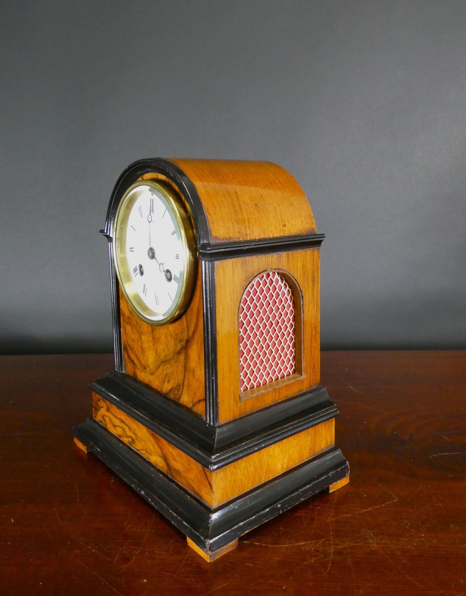 Victorian walnut cased mantle clock with break arch top and ebonised mouldings resting on a stepped plinth with pad feet. Decorative side silk lined sound frets.
Enamel dial with Roman numerals and original ‘blued’ steel Moonpoise hands.
French